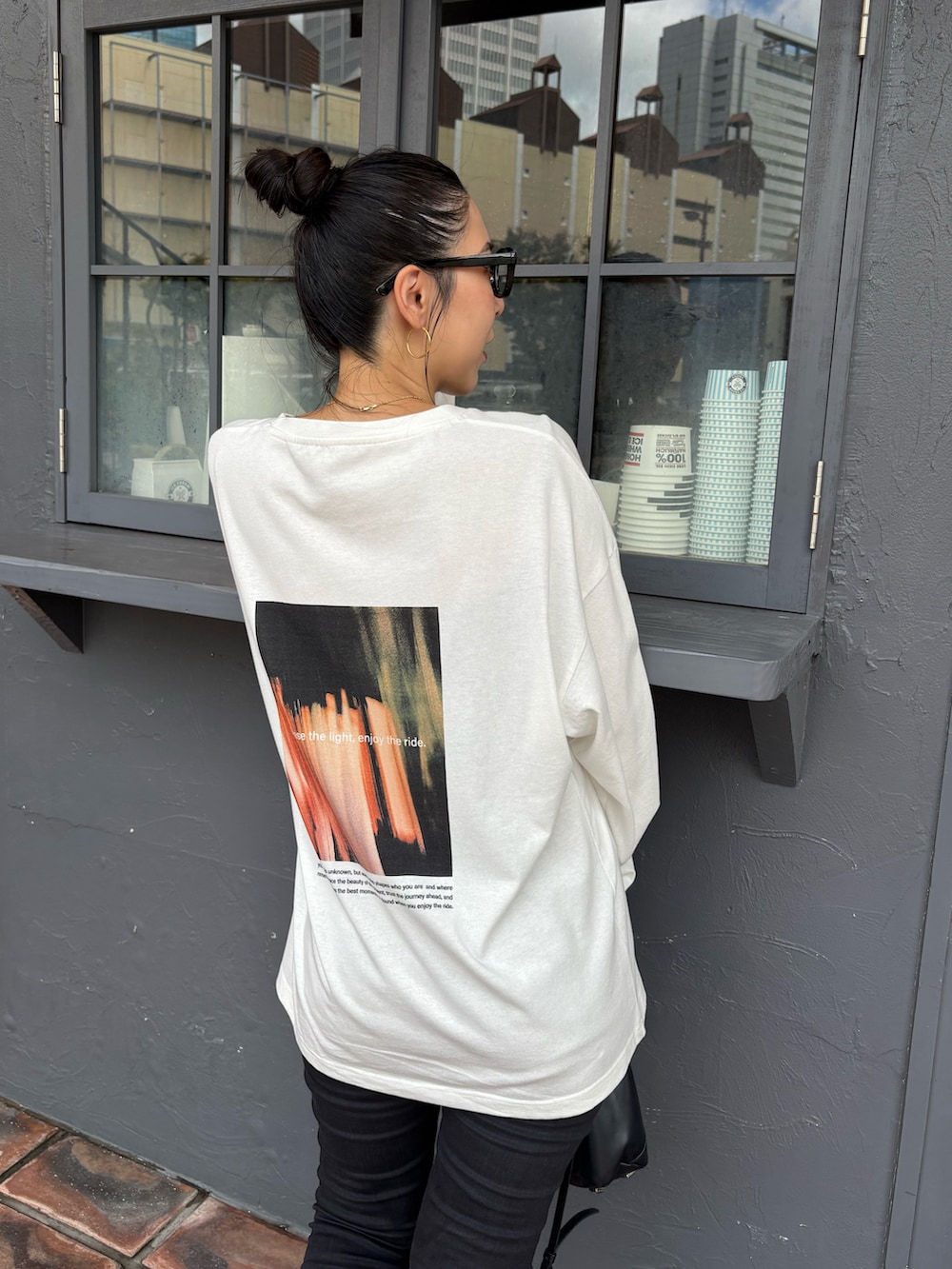 ブラック系のデニムパンツ、ブラック系のブーツ、ブラック系のショルダーバッグを着用したレディースの秋コーディネートの3枚目の写真