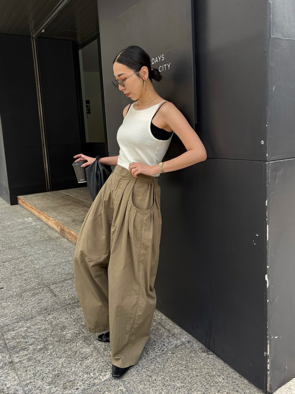 ブラック系のショルダーバッグ、ブラック系のサンダル、シルバー系のピアス（両耳用）を着用したレディースの春コーディネートの2枚目の写真