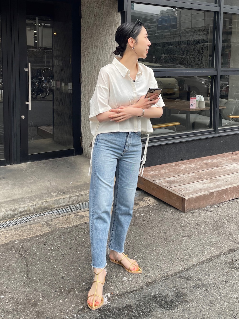 ブルー系のデニムパンツ、ゴールド系のサンダル、ホワイト系のシャツ/ブラウスを着用したレディースの春コーディネートの2枚目の写真