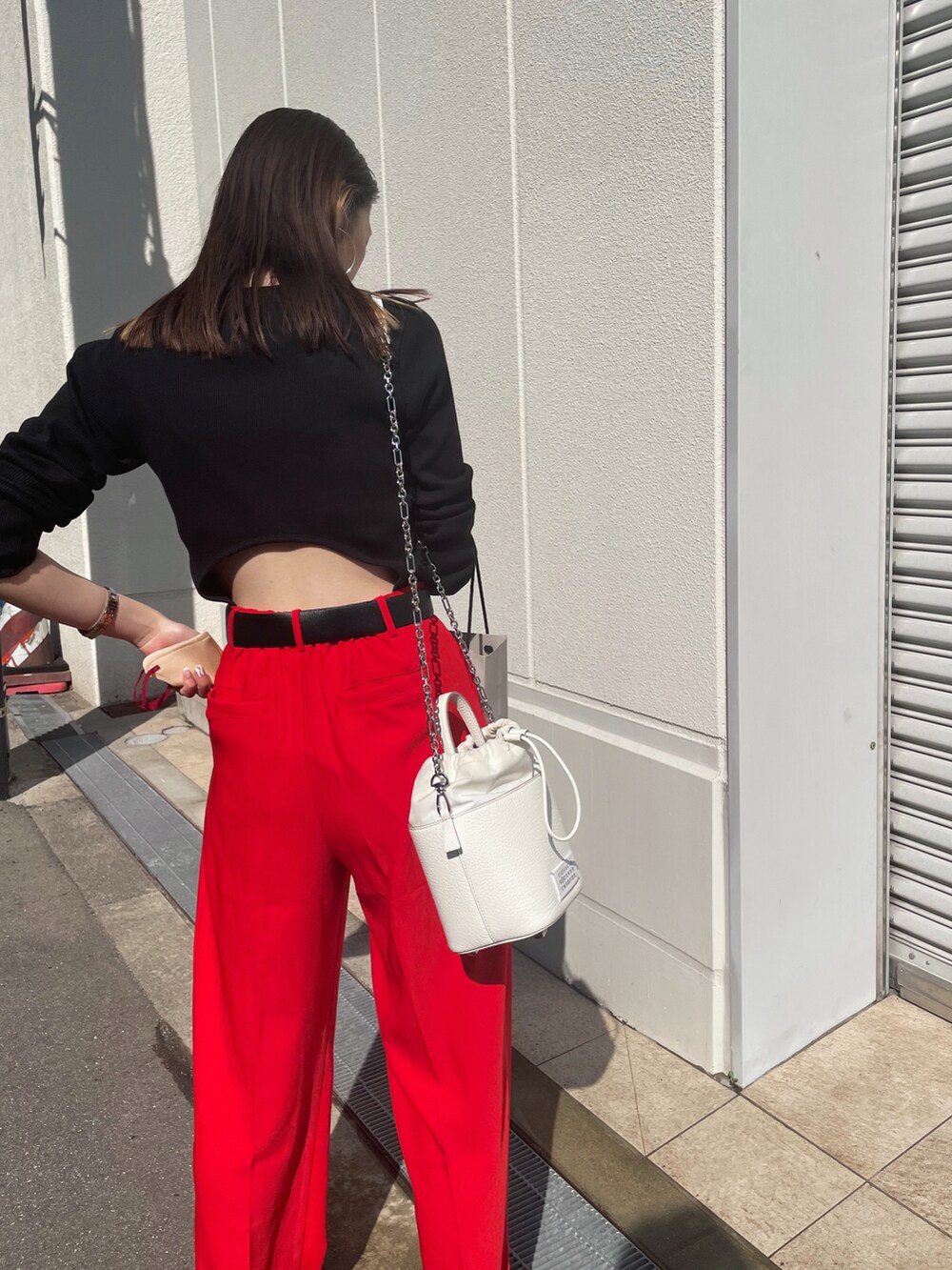 ブラック系のTシャツ/カットソー、レッド系のスラックス、ブラウン系のサンダルを着用したレディースの春コーディネートの4枚目の写真