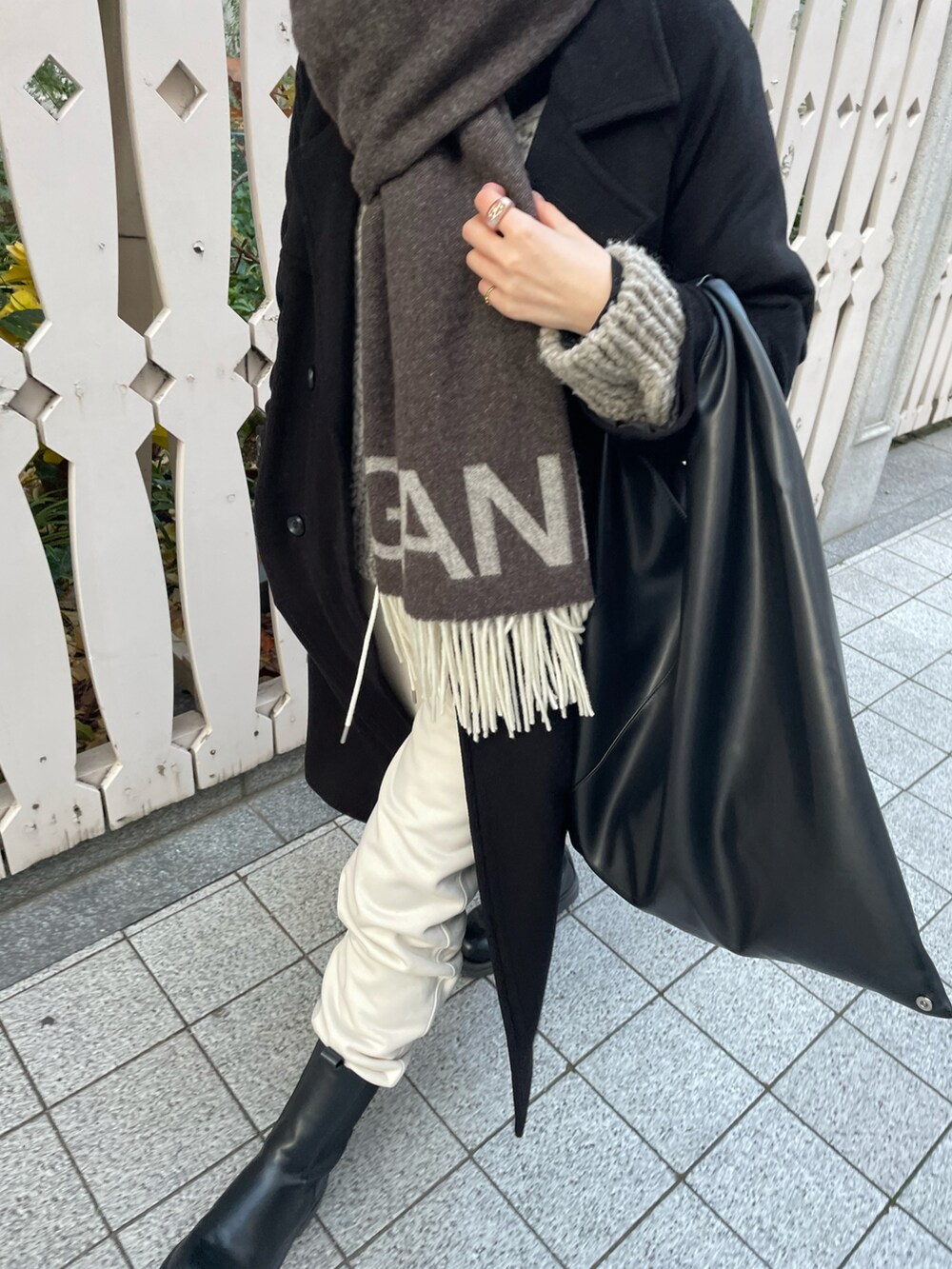 ブラック系のブーツ、ブラック系のハンドバッグ、ホワイト系のスウェットパンツを着用したレディースの冬コーディネートの4枚目の写真