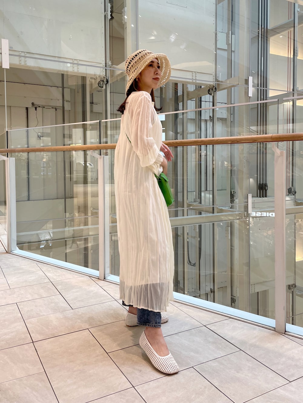 ホワイト系のワンピース、ホワイト系のパンプス、グリーン系のショルダーバッグを着用したレディースの春コーディネートの3枚目の写真