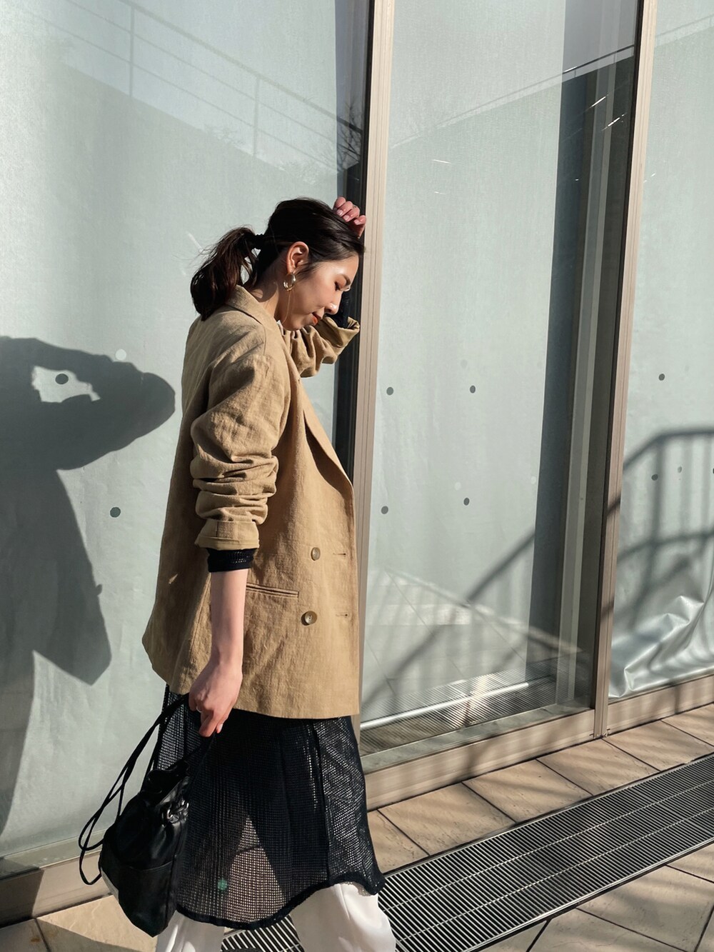 ベージュ系のテーラードジャケット、ブラック系のワンピース、ブラック系のショルダーバッグを着用したレディースの春コーディネートの3枚目の写真