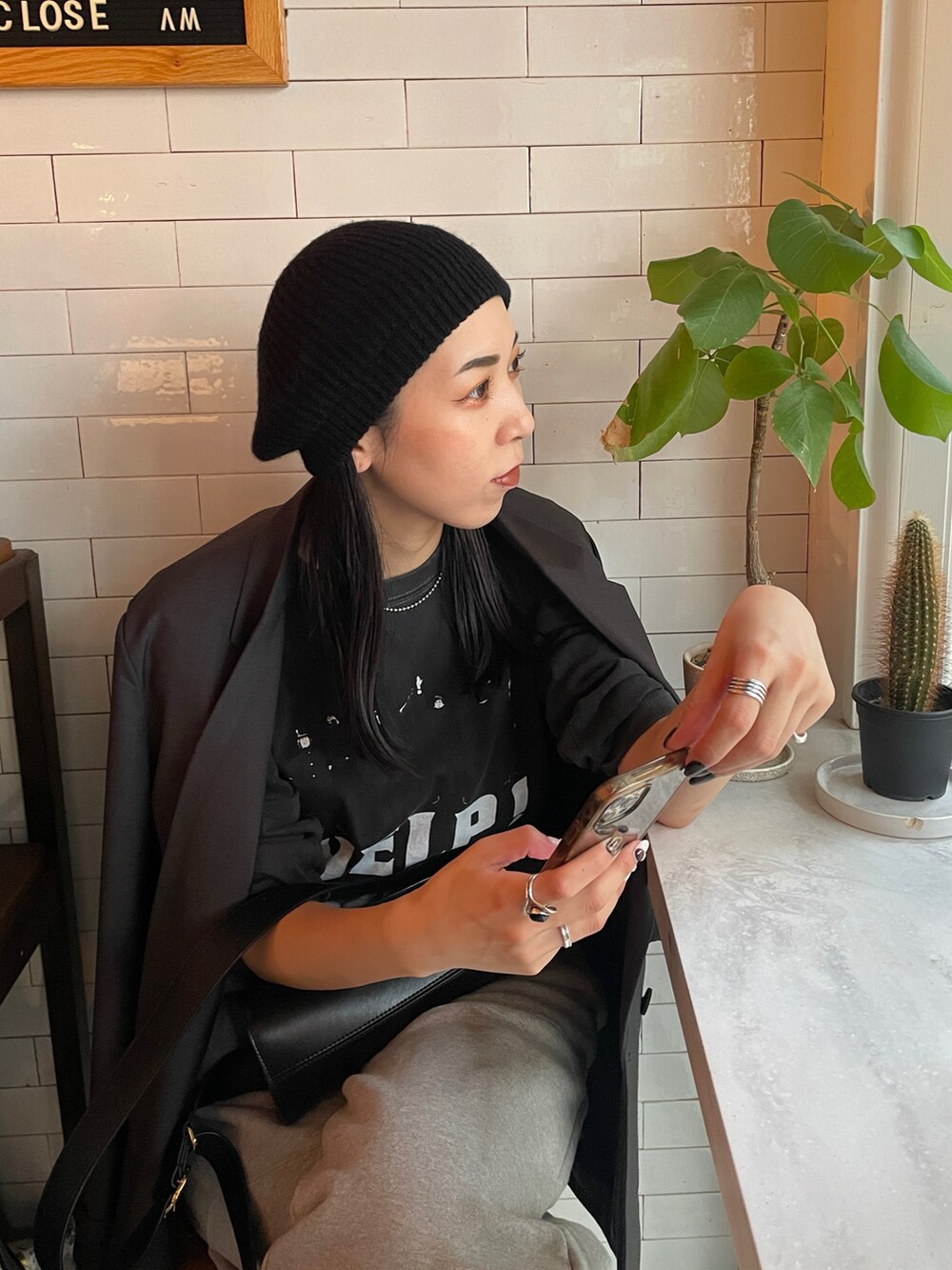 ブラック系のTシャツ/カットソー、ブラック系のショルダーバッグ、ブラック系のブーツを着用したレディースの秋コーディネートの5枚目の写真