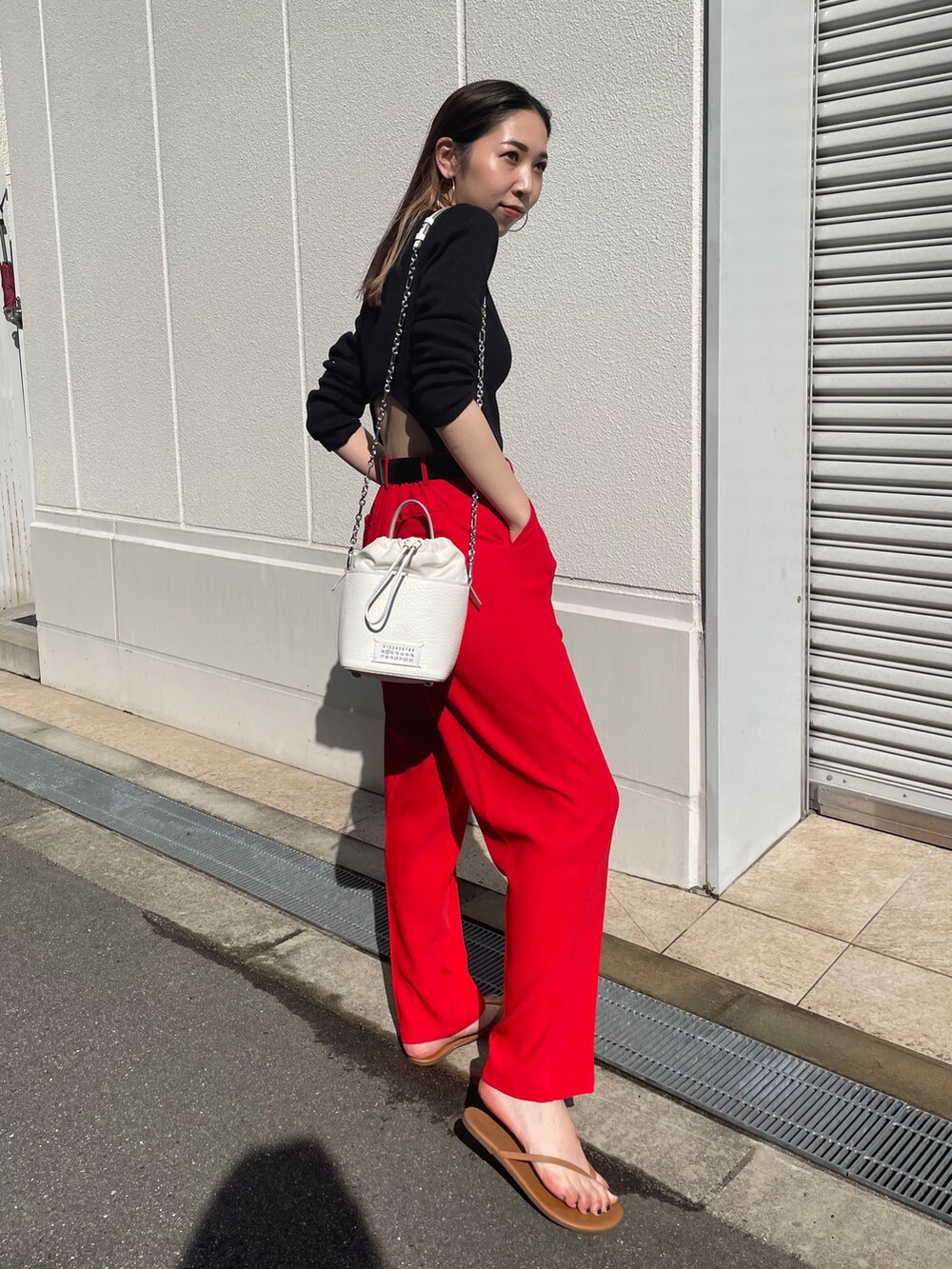 ブラック系のTシャツ/カットソー、レッド系のスラックス、ブラウン系のサンダルを着用したレディースの春コーディネートの2枚目の写真