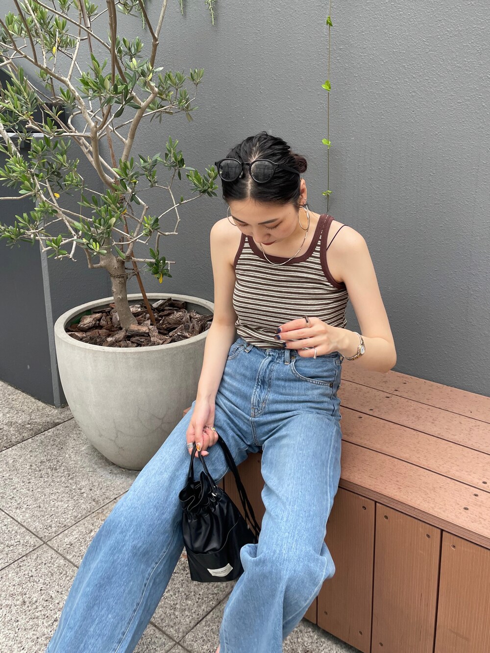 ブラック系のショルダーバッグ、ブラウン系のタンクトップ、ブルー系のデニムパンツを着用したレディースの夏コーディネートの5枚目の写真