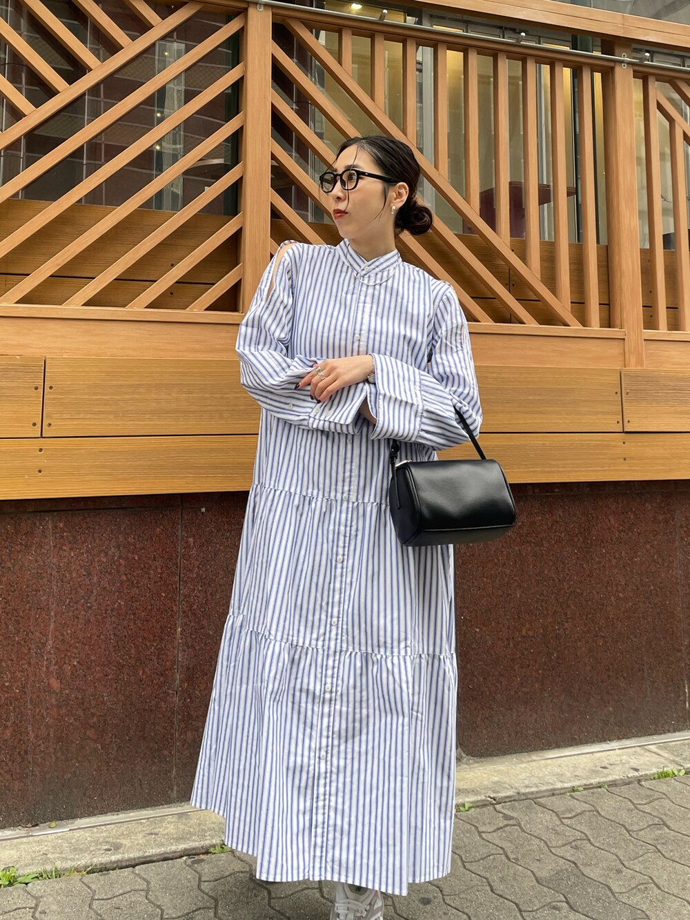 ブラック系のハンドバッグ、ホワイト系のスニーカー、その他のワンピースを着用したレディースの春コーディネートの2枚目の写真