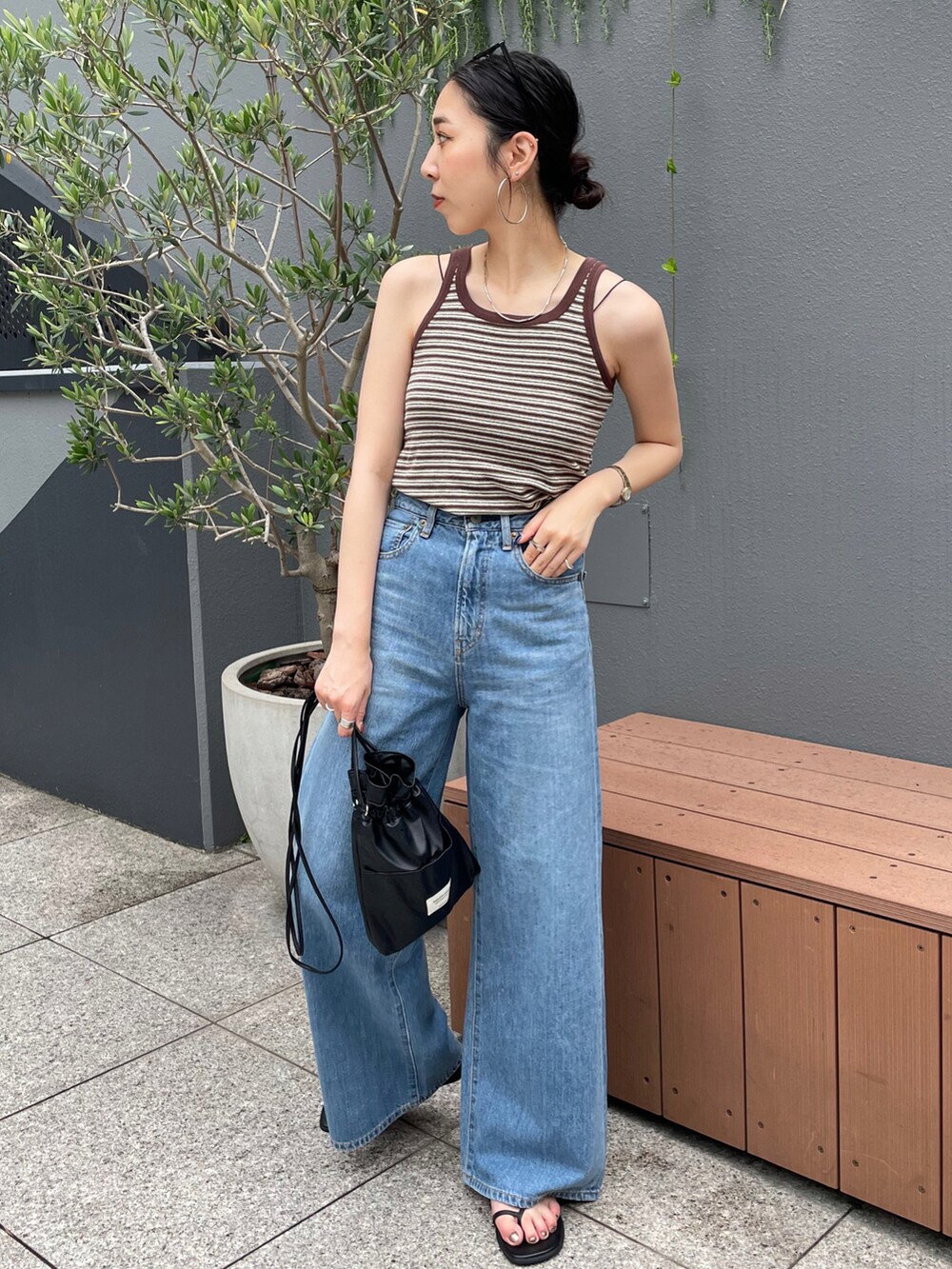 ブラック系のショルダーバッグ、ブラウン系のタンクトップ、ブルー系のデニムパンツを着用したレディースの夏コーディネートの3枚目の写真