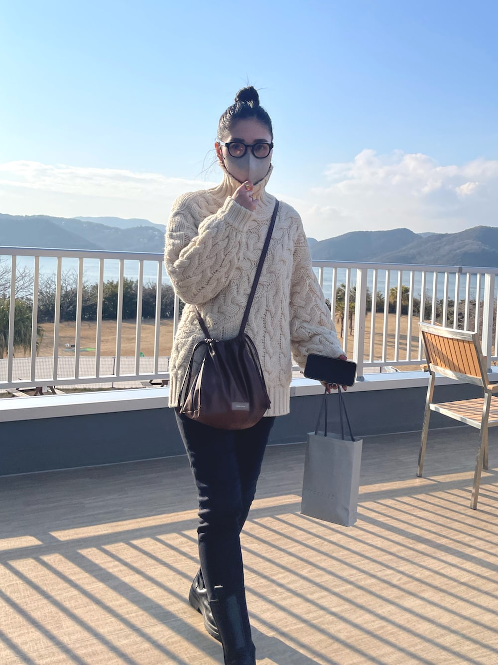 ブラウン系のショルダーバッグ、ブラック系のデニムパンツ、ブラック系のブーツを着用したレディースの冬コーディネートの3枚目の写真