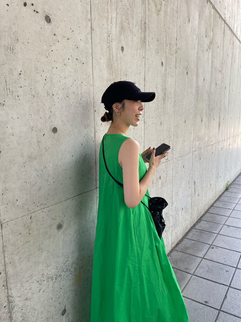 ブラック系のショルダーバッグ、グリーン系のワンピース、ブラック系のサンダルを着用したレディースの夏コーディネートの2枚目の写真