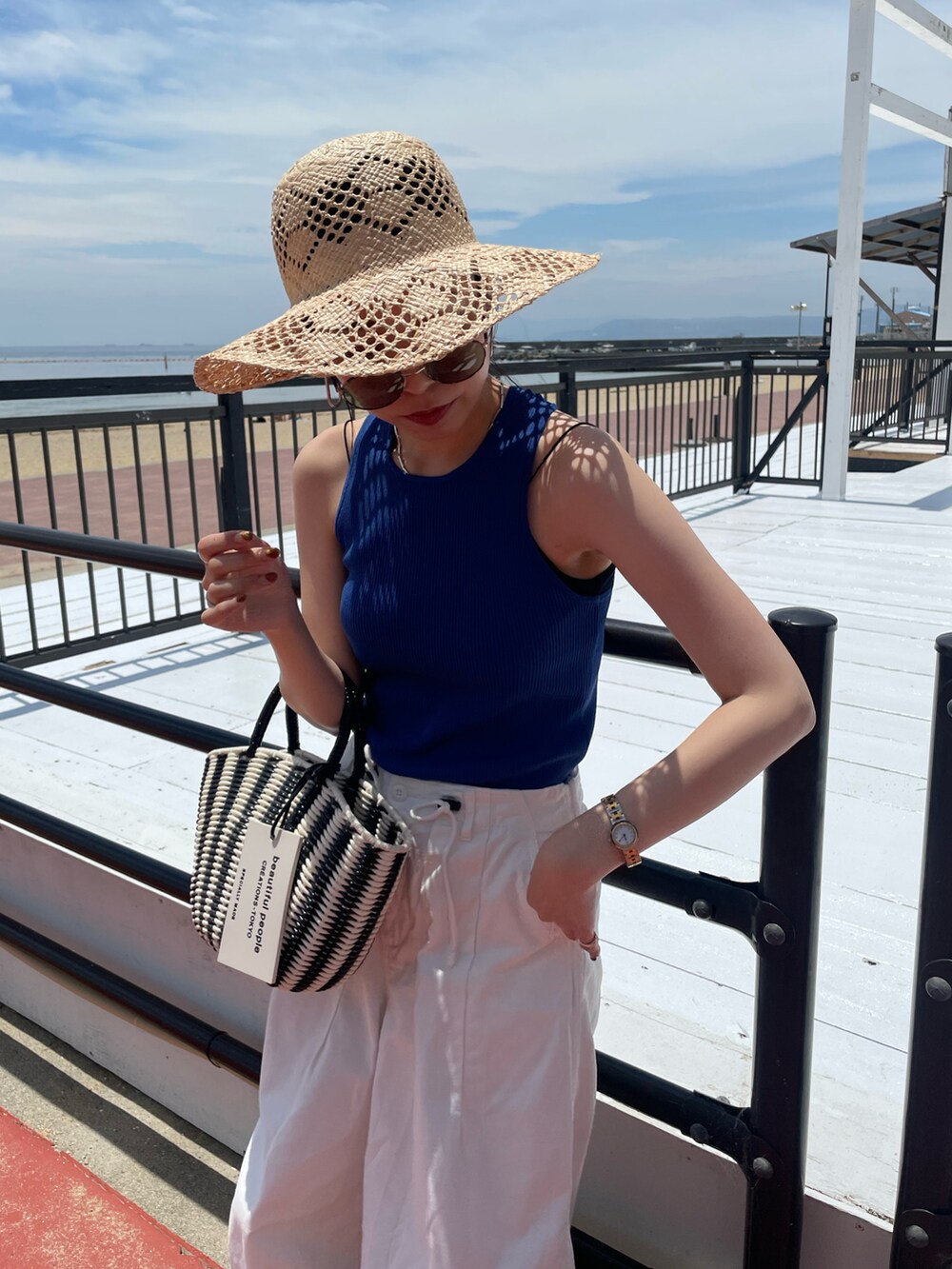 ブルー系のタンクトップ、ブラック系のハンドバッグ、ホワイト系のその他パンツを着用したレディースの夏コーディネートの3枚目の写真