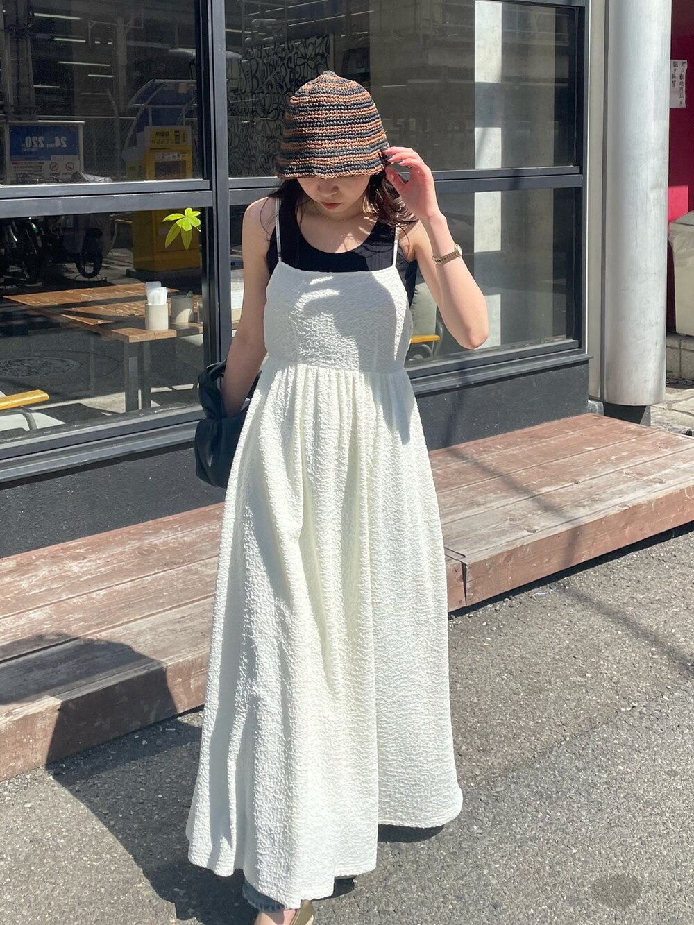 ブラック系のハンドバッグ、ホワイト系のワンピース、ゴールド系のパンプスを着用したレディースの春コーディネートの5枚目の写真