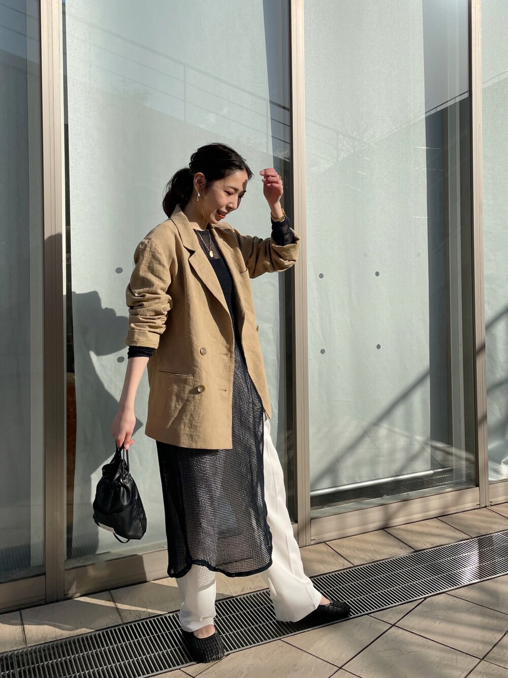 ベージュ系のテーラードジャケット、ブラック系のワンピース、ブラック系のショルダーバッグを着用したレディースの春コーディネートの4枚目の写真