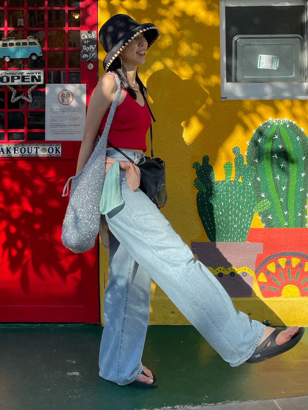 ブラック系のサンダル、ブルー系のデニムパンツ、ブラック系のショルダーバッグを着用したレディースの秋コーディネートの4枚目の写真