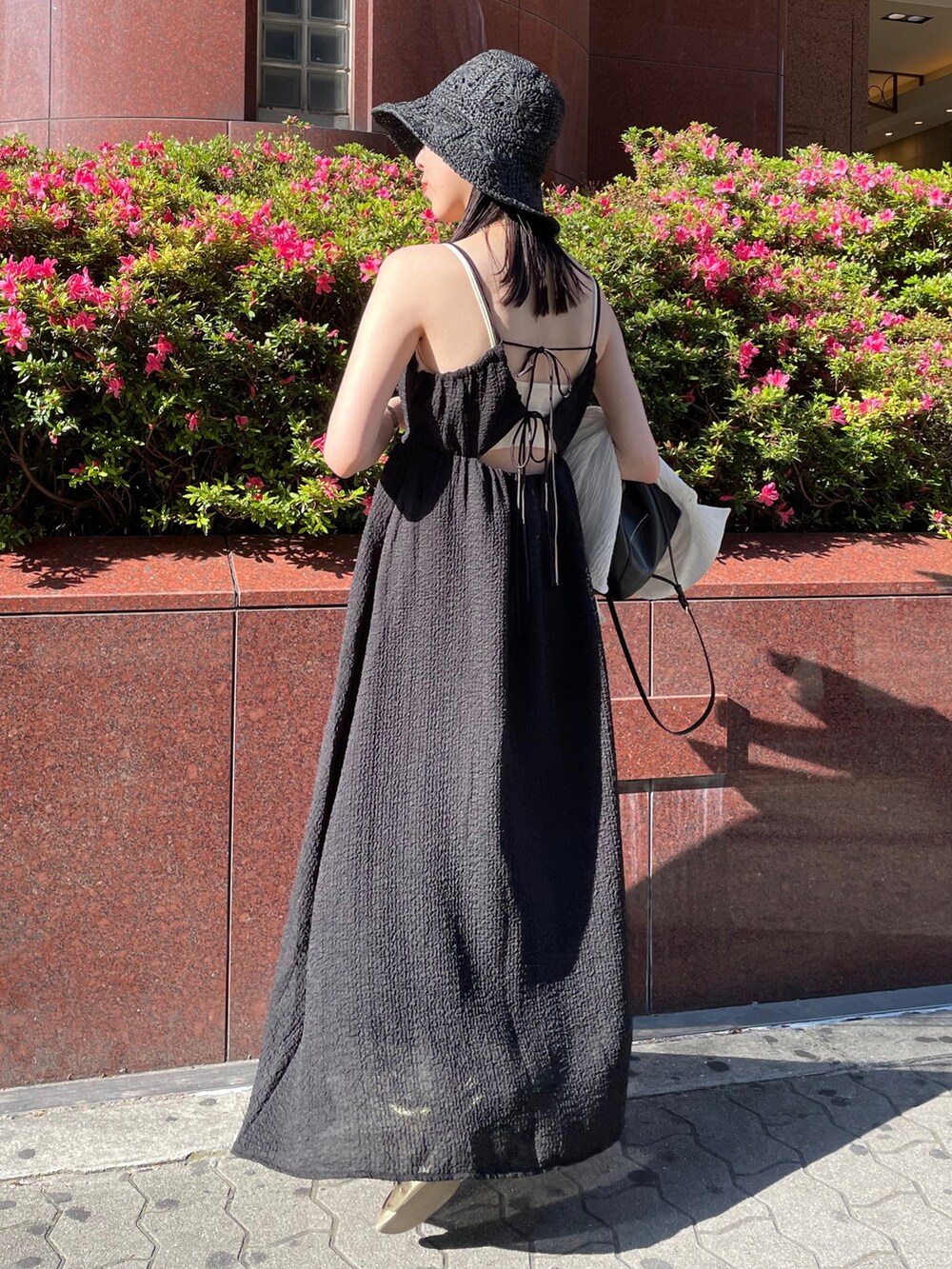 ブラック系のワンピース、ゴールド系のパンプス、ホワイト系のシャツ/ブラウスを着用したレディースの春コーディネートの2枚目の写真