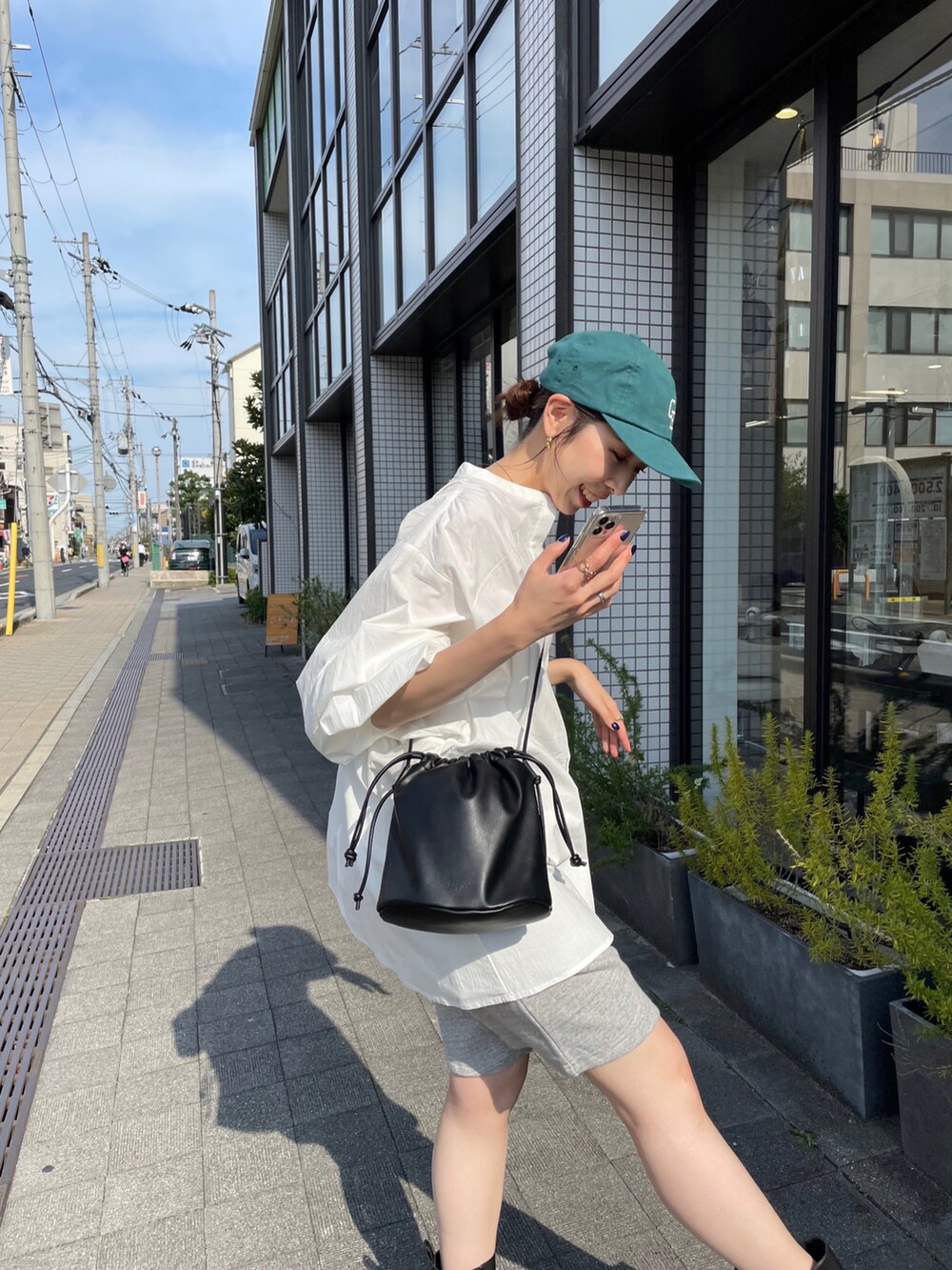 ホワイト系のシャツ/ブラウス、ブラック系のハンドバッグ、ブラック系のブーツを着用したレディースの夏コーディネートの3枚目の写真