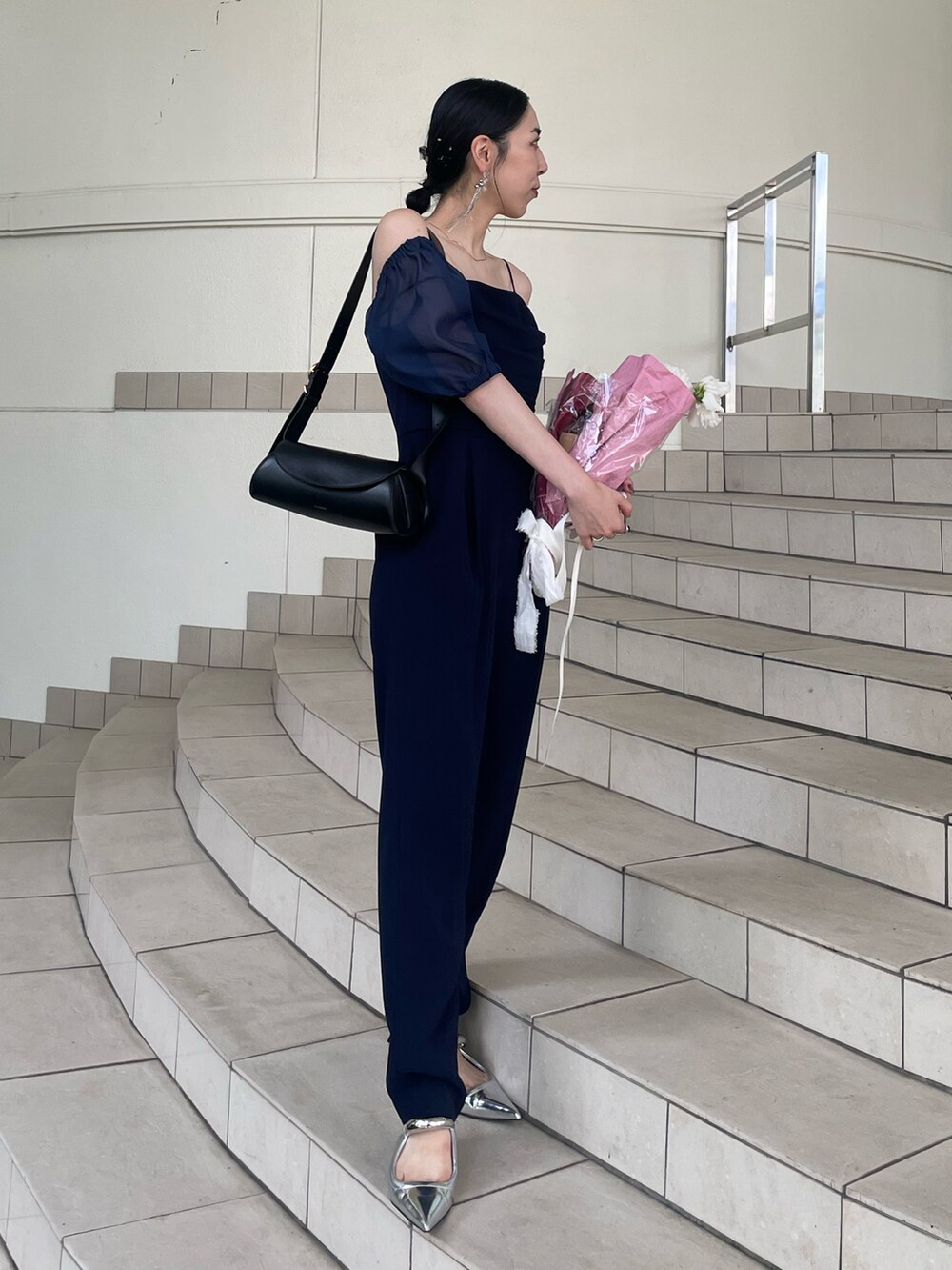 シルバー系のパンプス、ブルー系のドレス、ブラック系のショルダーバッグを着用したレディースの夏コーディネートの2枚目の写真