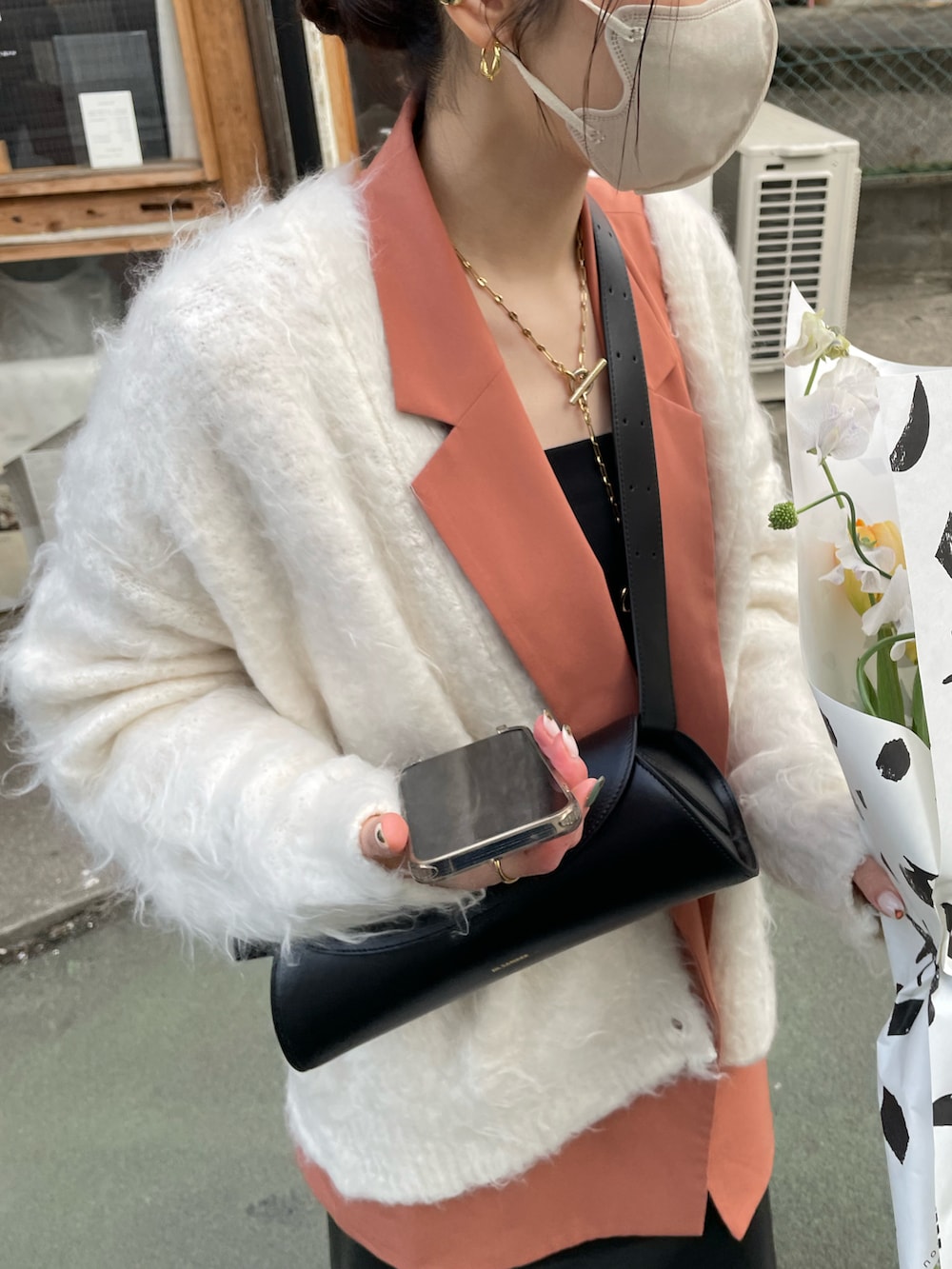 ブラック系のショルダーバッグ、ブラック系のスカート、ホワイト系のカーディガン/ボレロを着用したレディースの冬コーディネートの5枚目の写真