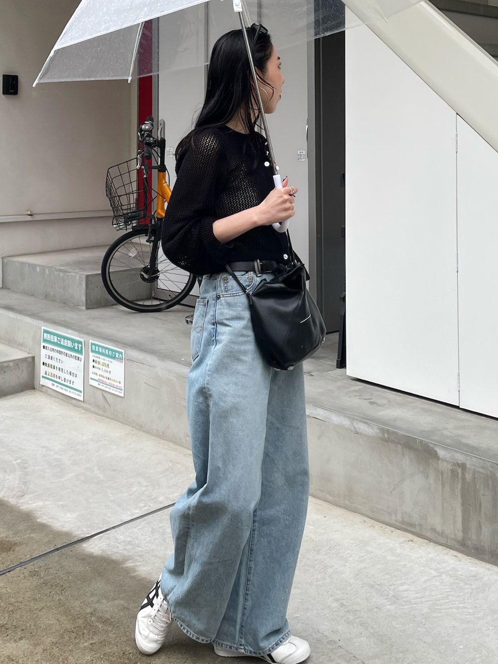 ブルー系のデニムパンツ、ブラック系のカーディガン/ボレロ、ブラック系のショルダーバッグを着用したレディースの春コーディネートの2枚目の写真