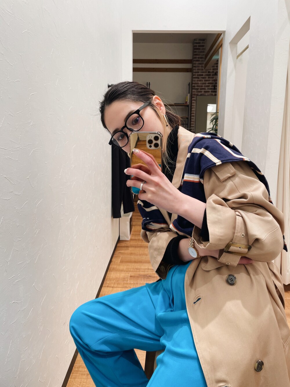 ブルー系のスラックス、ベージュ系のトレンチコート、ブルー系のTシャツ/カットソーを着用したレディースの冬コーディネートの2枚目の写真