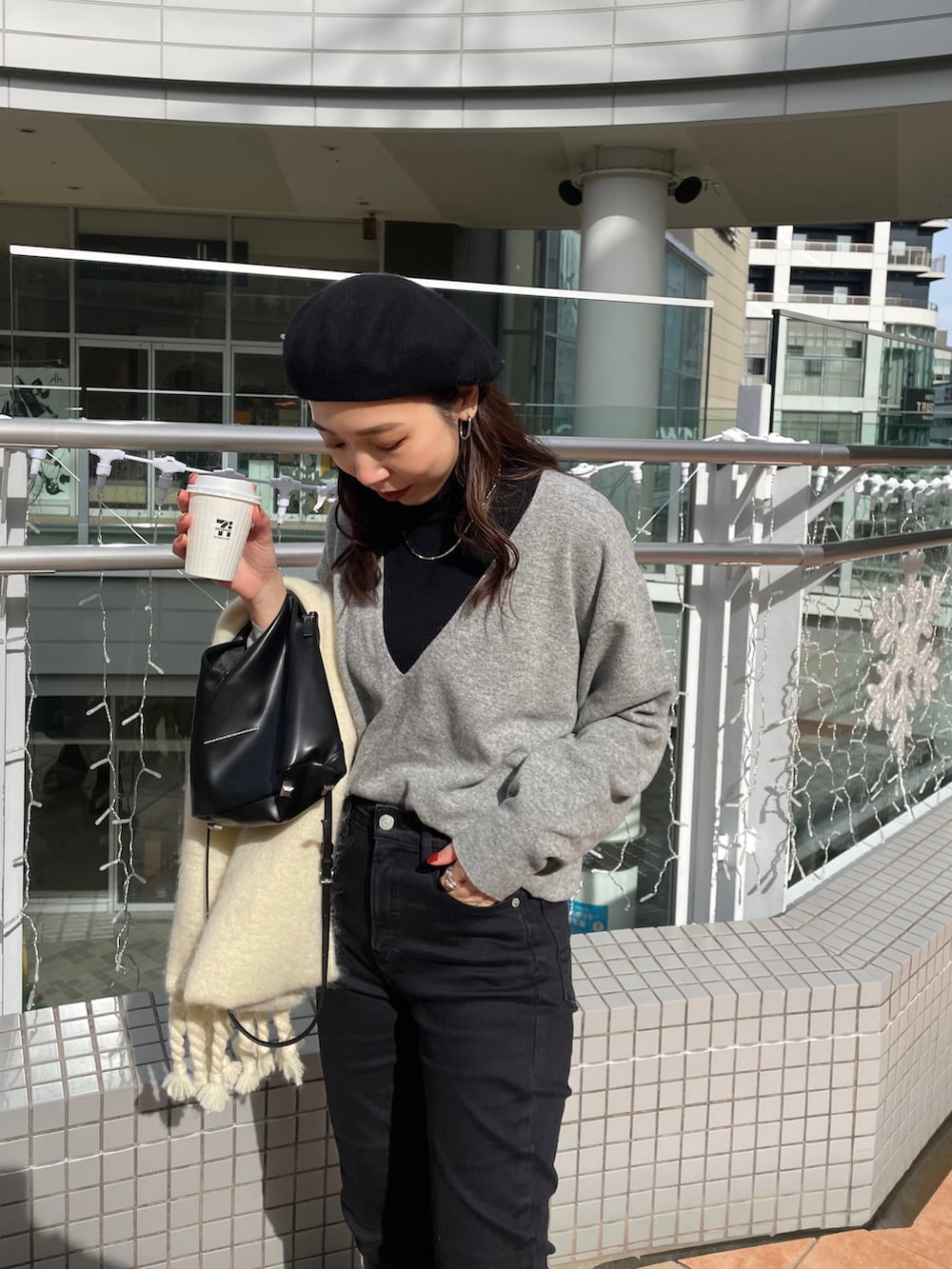 ブラック系のブーツ、ブラック系のデニムパンツ、ブラック系のショルダーバッグを着用したレディースの冬コーディネートの4枚目の写真