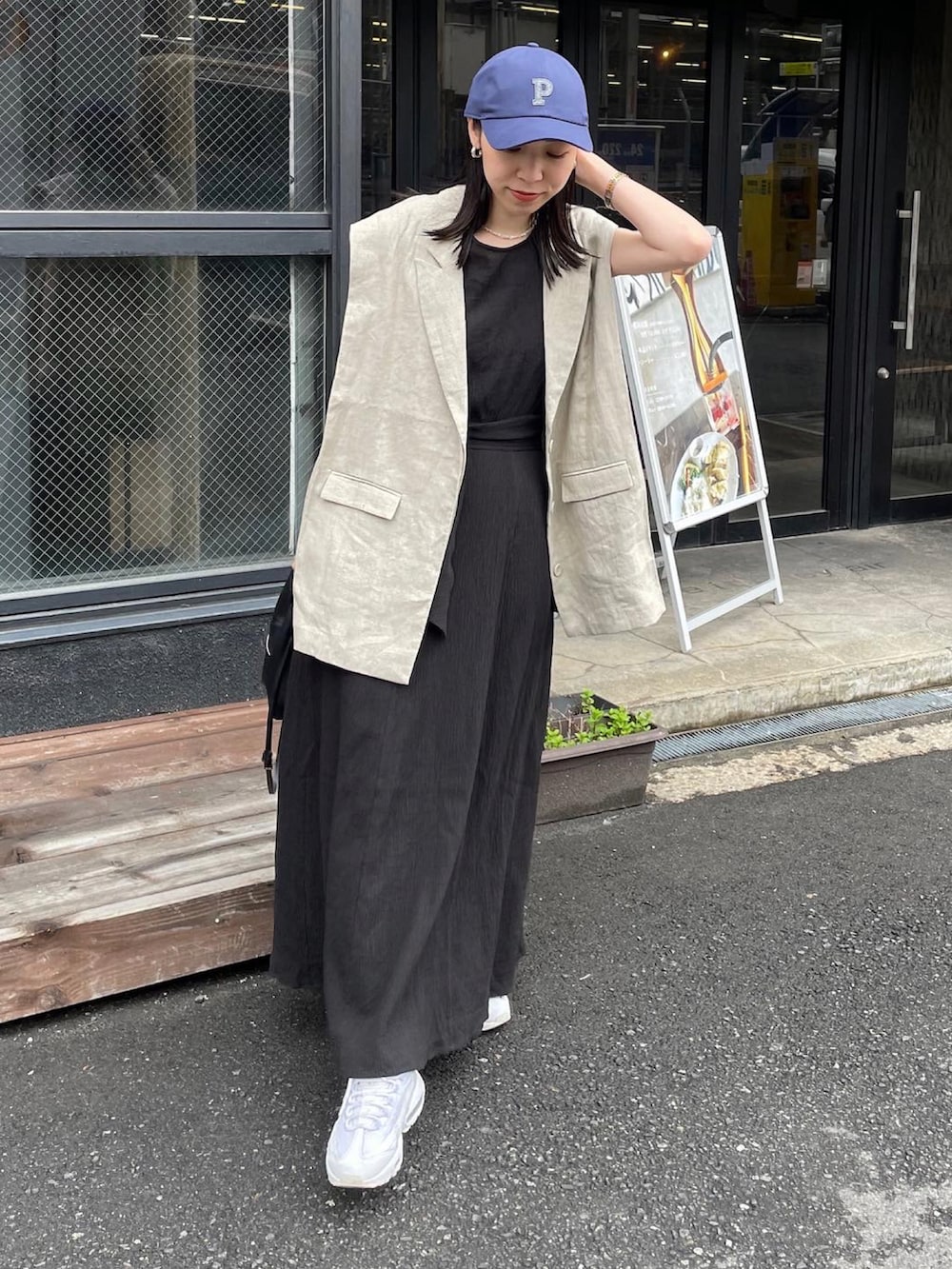 ベージュ系のベスト、ブラック系のショルダーバッグ、ブラック系のワンピースを着用したレディースの春コーディネートの3枚目の写真