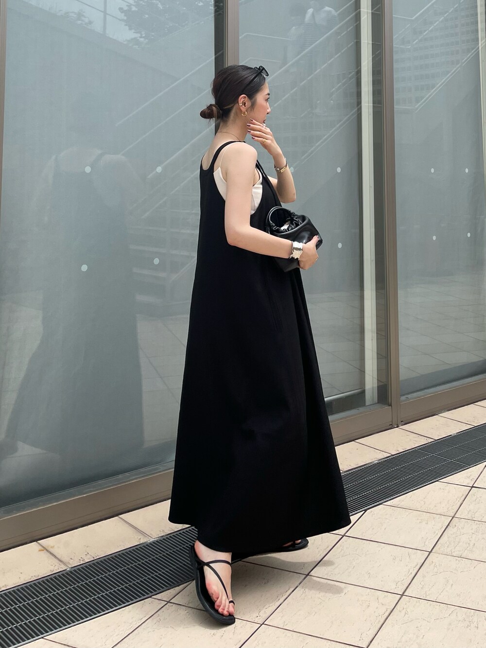 ブラック系のハンドバッグ、ブラック系のワンピース、ブラック系のサンダルを着用したレディースの夏コーディネートの5枚目の写真