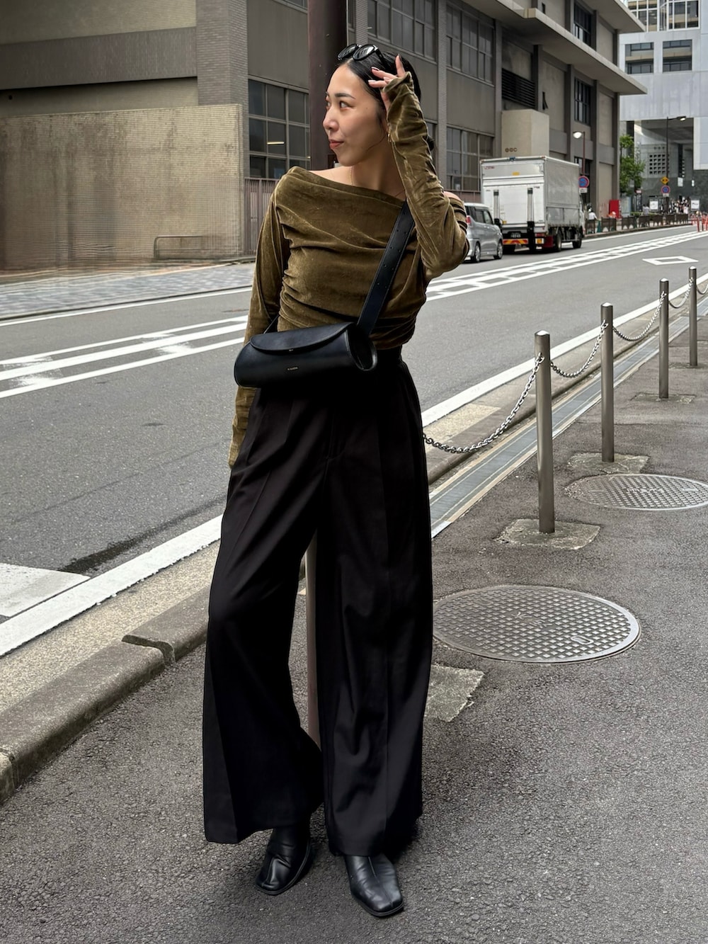 ブラック系のスラックス、ブラック系のショルダーバッグ、ブラック系のブーツを着用したレディースの秋コーディネートの3枚目の写真