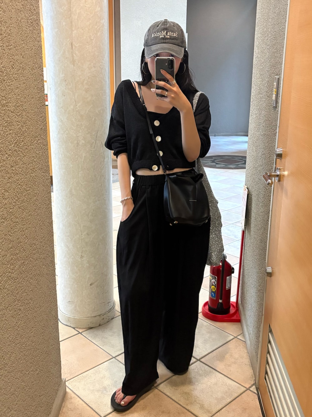 ブラック系のサンダル、ブラック系のショルダーバッグ、シルバー系のトートバッグを着用したレディースの夏コーディネートの2枚目の写真