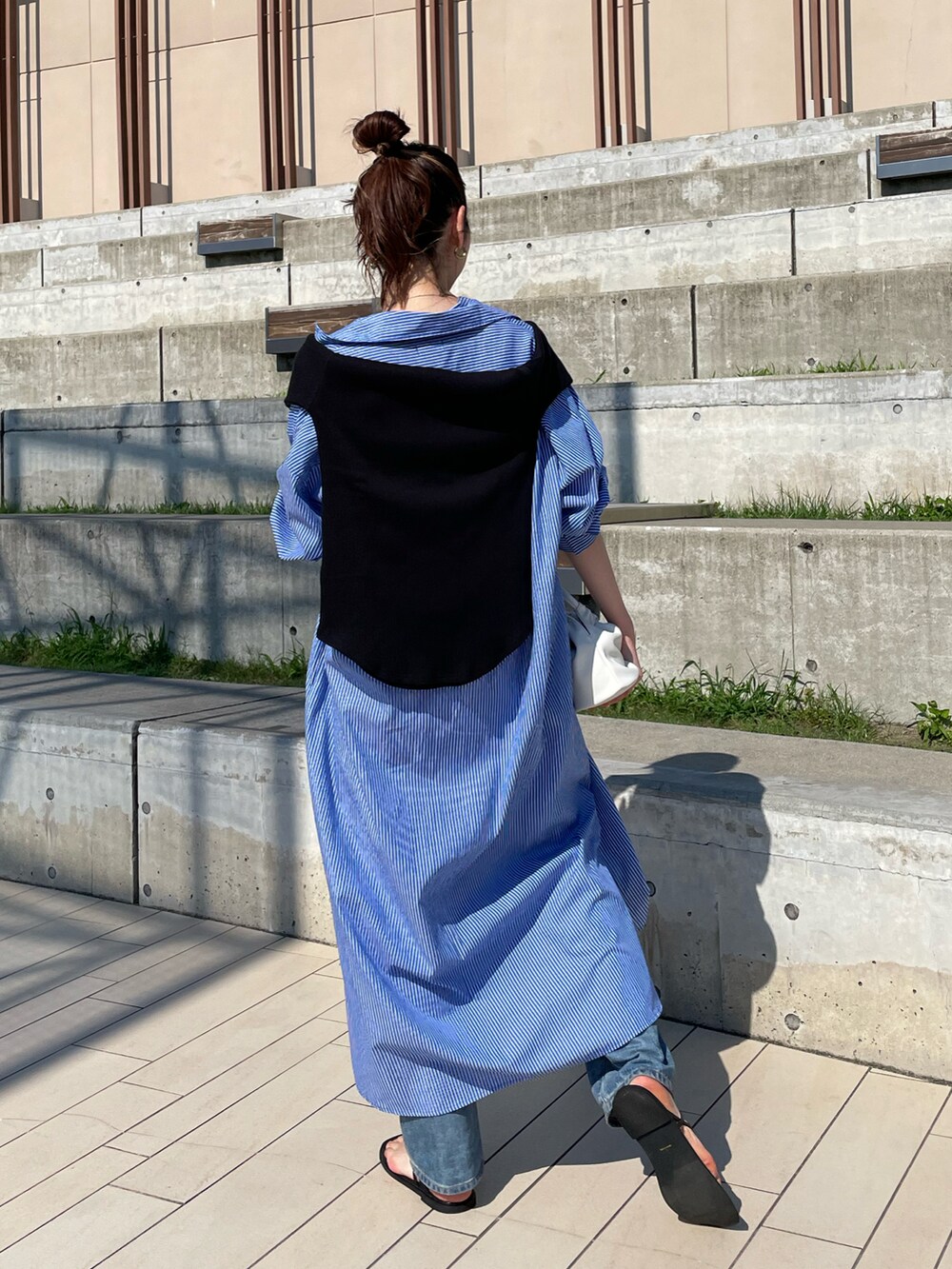 ブルー系のワンピース、ホワイト系のハンドバッグ、ブラック系のサンダルを着用したレディースの夏コーディネートの2枚目の写真