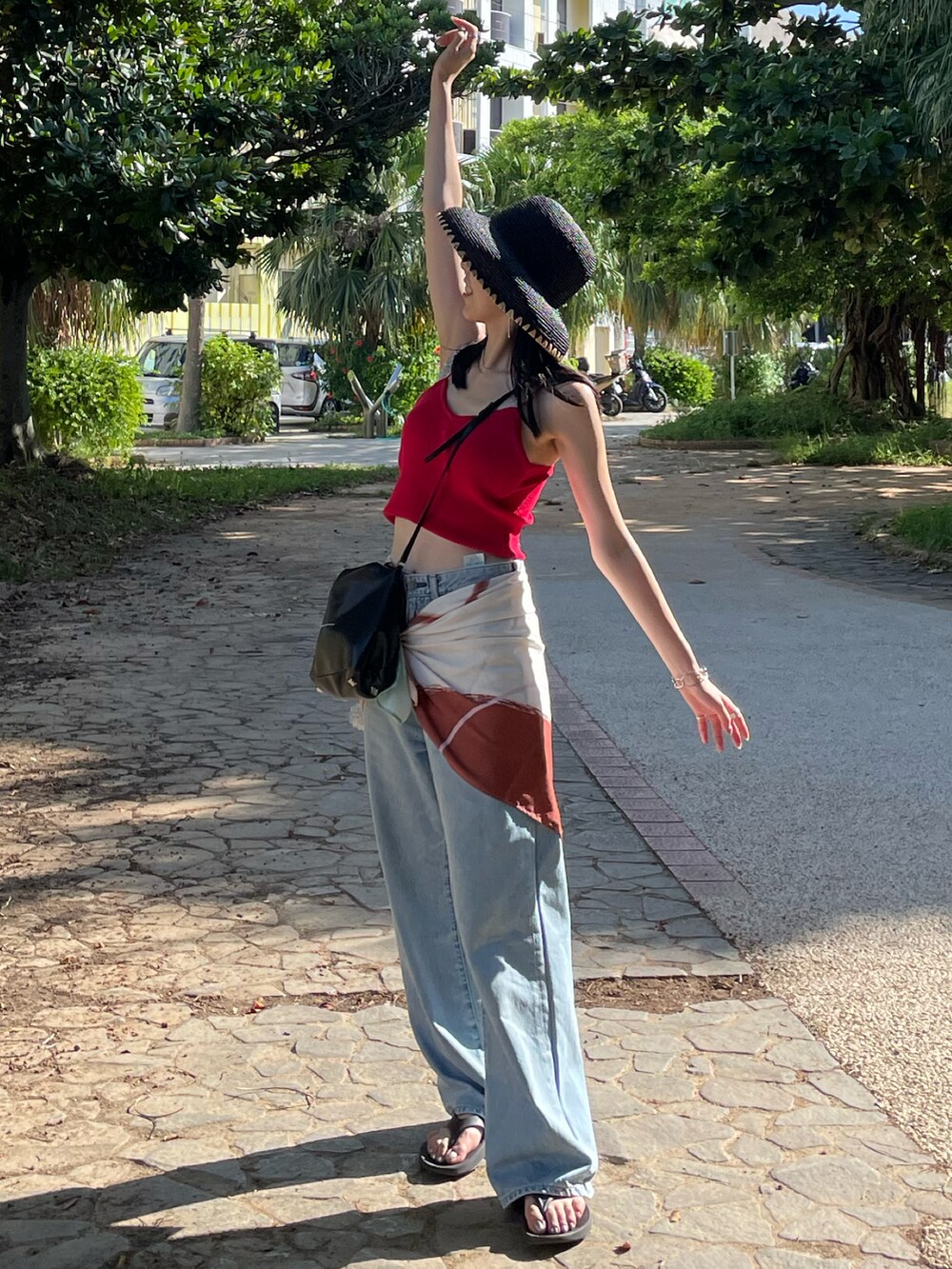 ブラック系のサンダル、ブルー系のデニムパンツ、ブラック系のショルダーバッグを着用したレディースの秋コーディネートの2枚目の写真