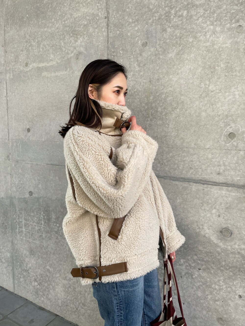 ホワイト系のブルゾン、ブルー系のデニムパンツ、レッド系のトートバッグを着用したレディースの冬コーディネートの4枚目の写真