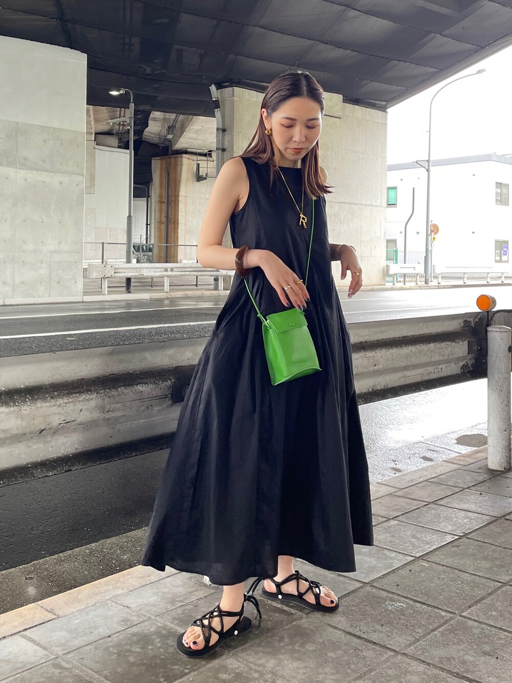 ブラック系のワンピース、ブラック系のサンダル、グリーン系のショルダーバッグを着用したレディースの春コーディネートの4枚目の写真
