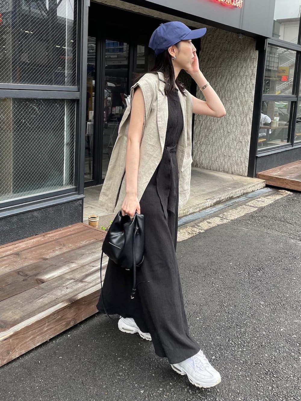 ベージュ系のベスト、ブラック系のショルダーバッグ、ブラック系のワンピースを着用したレディースの春コーディネートの2枚目の写真