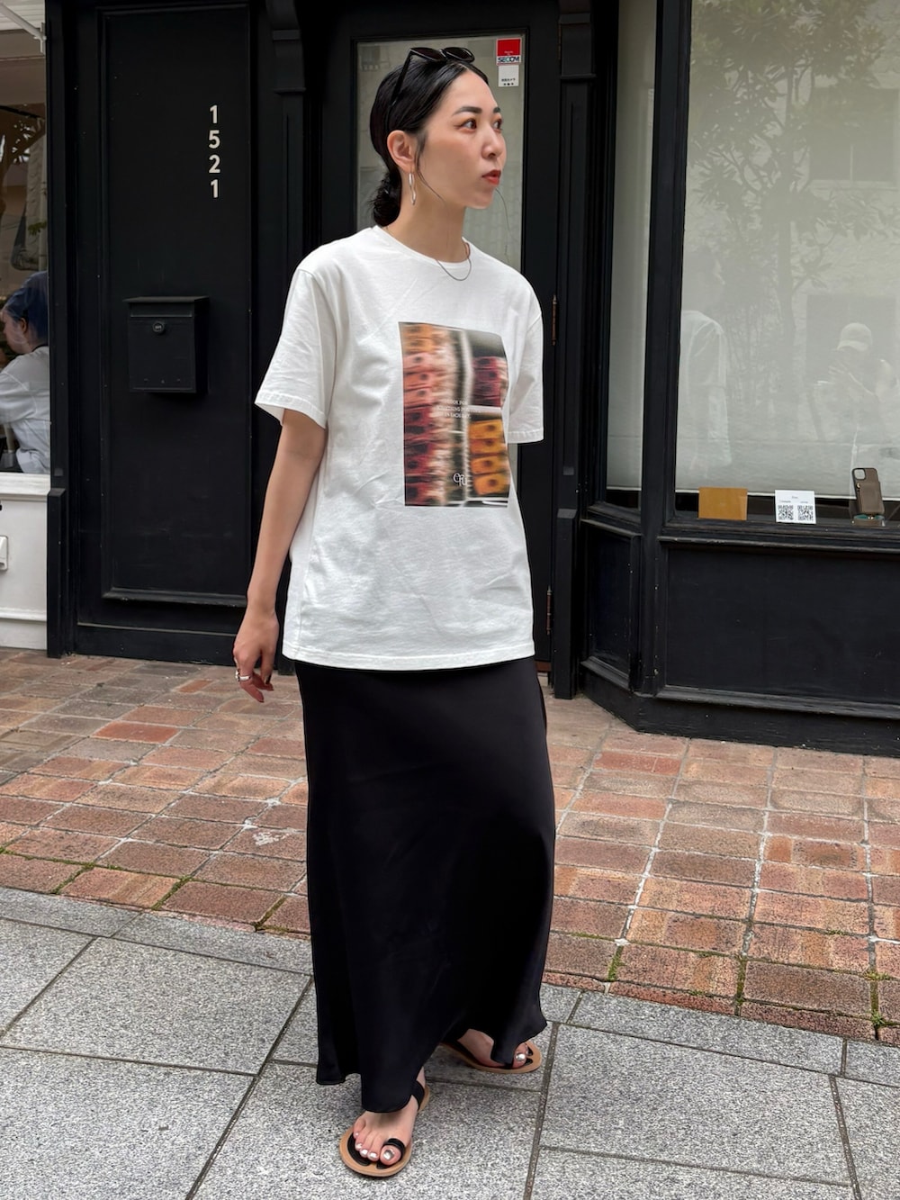 ブラック系のサンダル、ブラック系のショルダーバッグ、シルバー系のネックレスを着用したレディースの夏コーディネートの2枚目の写真