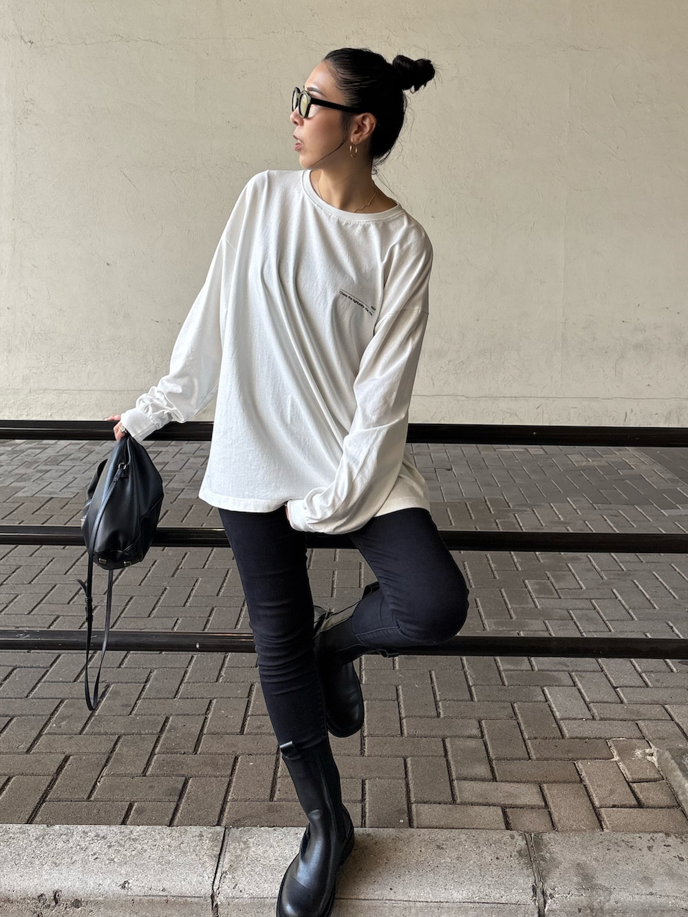 ブラック系のデニムパンツ、ブラック系のブーツ、ブラック系のショルダーバッグを着用したレディースの秋コーディネートの4枚目の写真