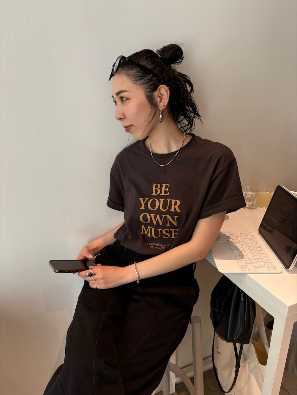 ブラック系のショルダーバッグ、ゴールド系のパンプス、シルバー系のネックレスを着用したレディースの春コーディネートの2枚目の写真