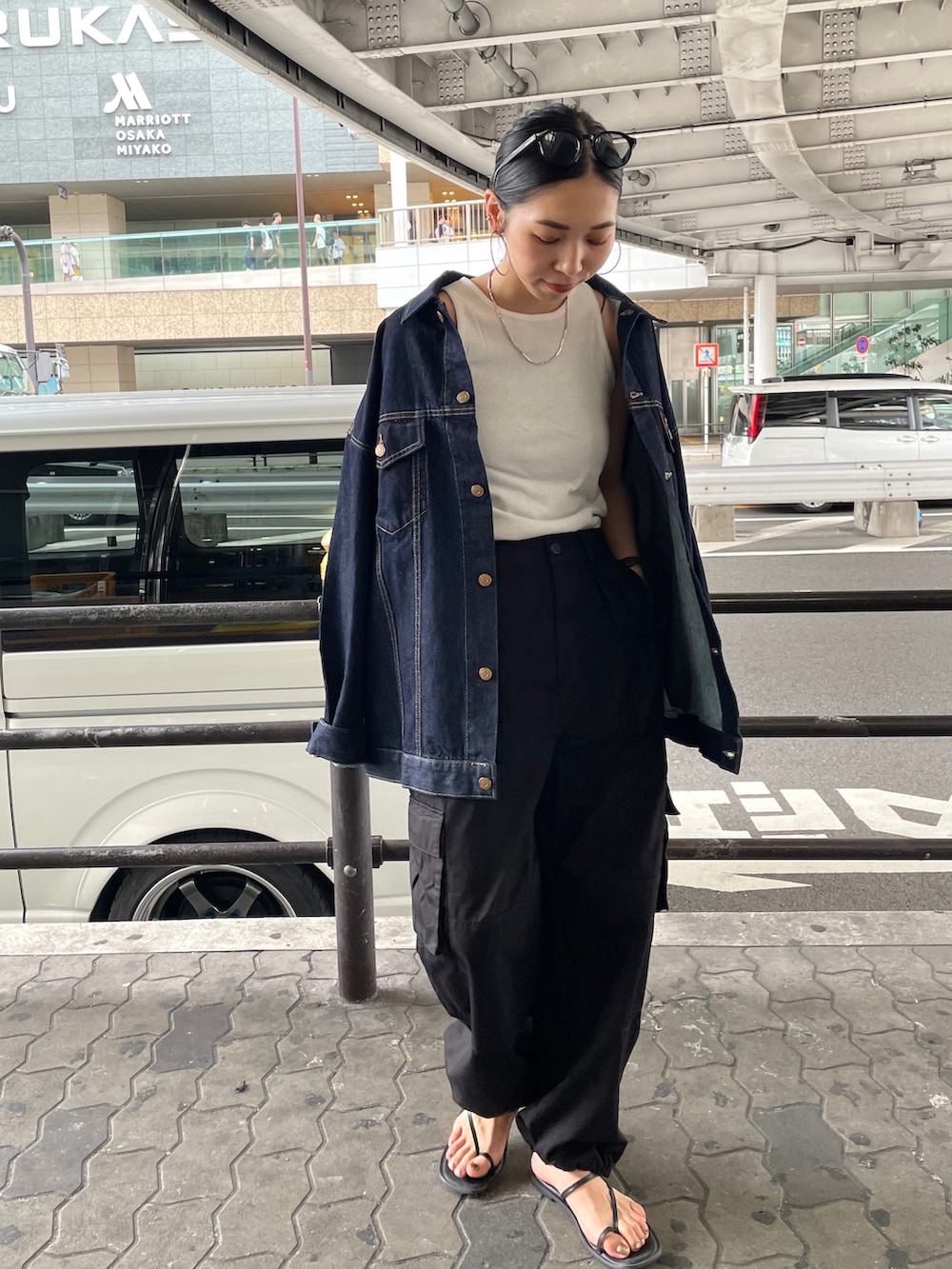 ブルー系のデニムジャケット、ブラック系のカーゴパンツ、ブラック系のサンダルを着用したレディースの夏コーディネートの5枚目の写真