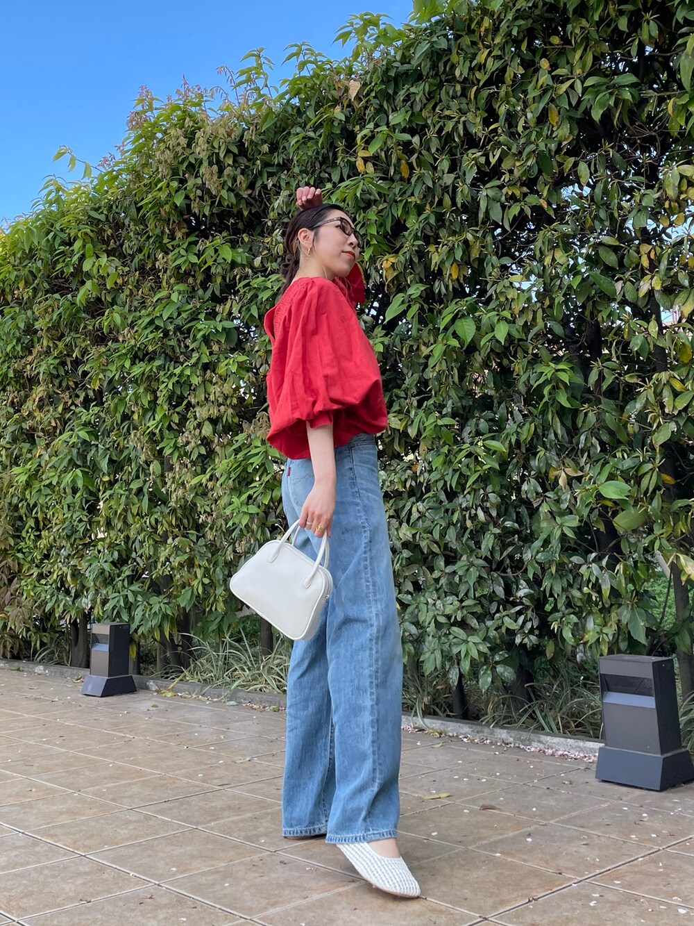 レッド系のシャツ/ブラウス、ブルー系のデニムパンツ、ホワイト系のパンプスを着用したレディースの春コーディネートの2枚目の写真