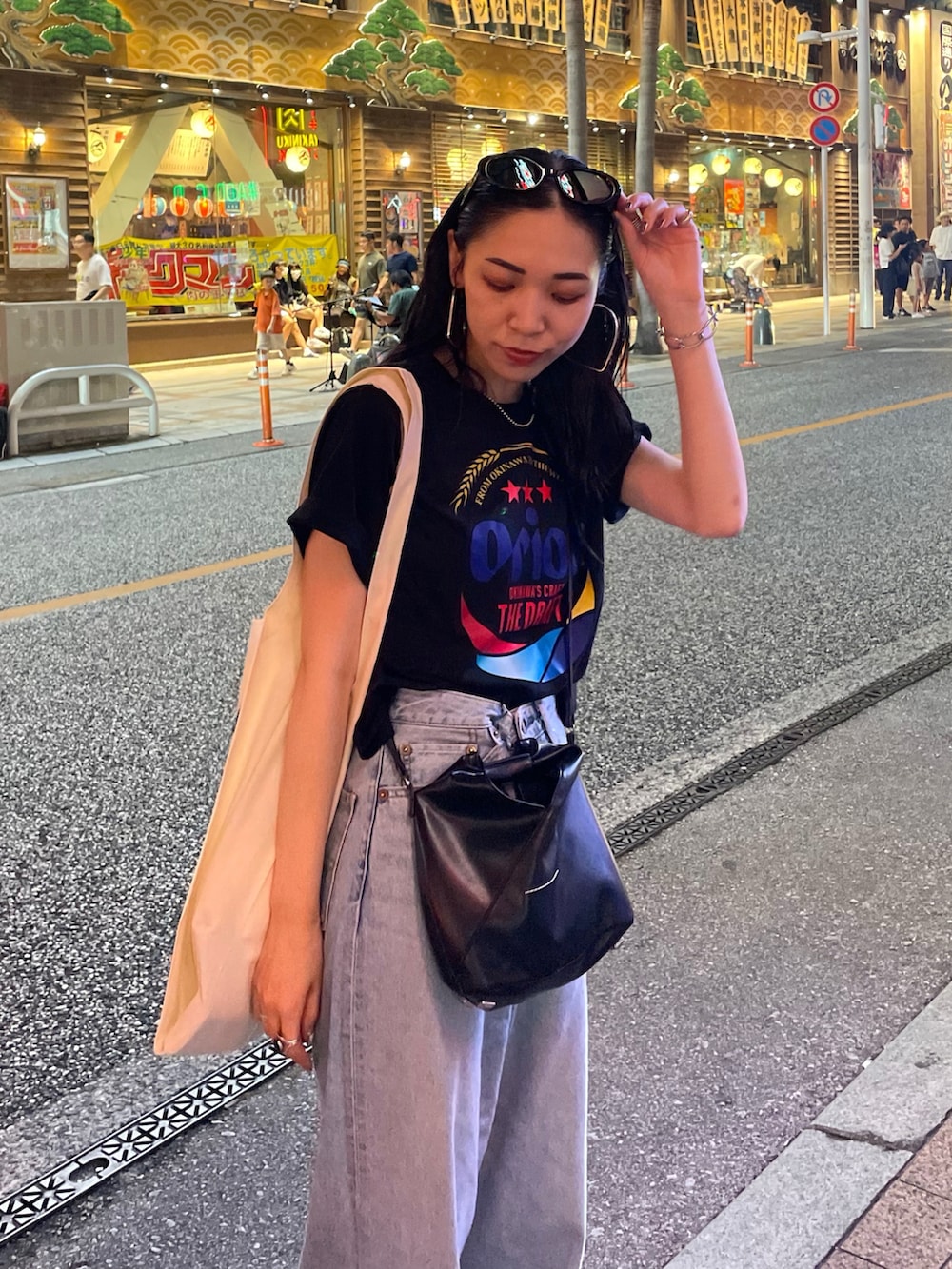 ブルー系のデニムパンツ、ブラック系のショルダーバッグ、ブラック系のサンダルを着用したレディースの秋コーディネートの4枚目の写真