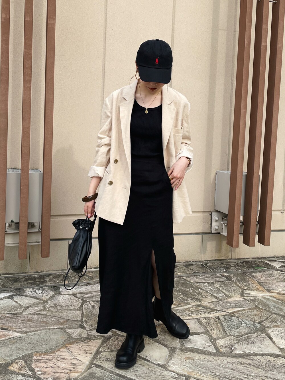 ブラック系のショルダーバッグ、ホワイト系のテーラードジャケット、ブラック系のスカートを着用したレディースの春コーディネートの3枚目の写真
