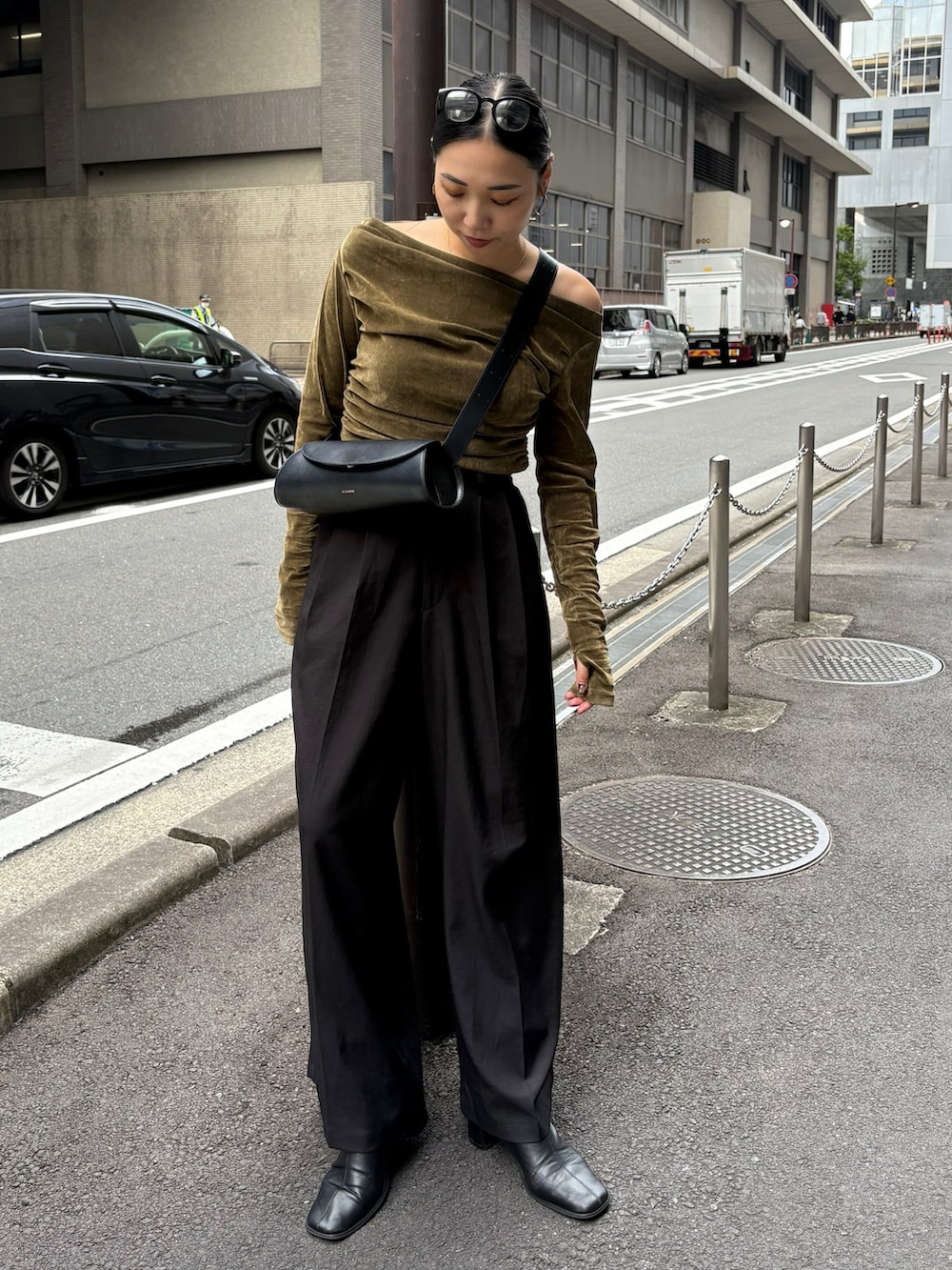 ブラック系のスラックス、ブラック系のショルダーバッグ、ブラック系のブーツを着用したレディースの秋コーディネートの2枚目の写真