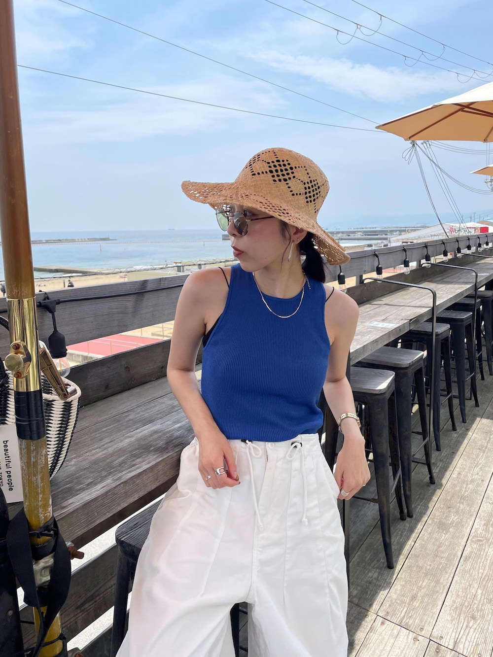 ブルー系のタンクトップ、ブラック系のハンドバッグ、ホワイト系のその他パンツを着用したレディースの夏コーディネートの4枚目の写真