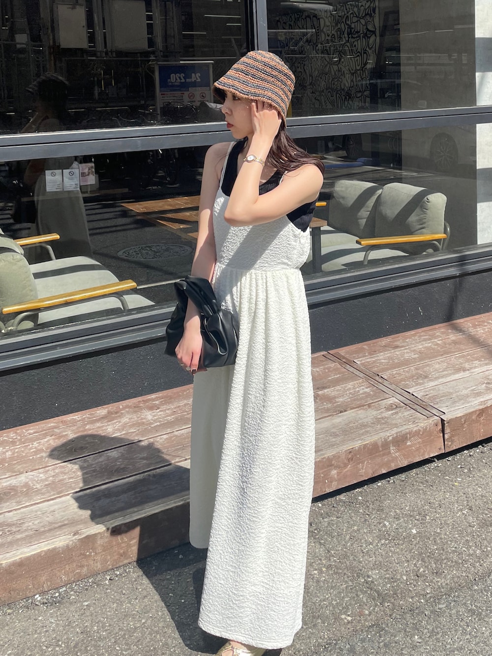 ブラック系のハンドバッグ、ホワイト系のワンピース、ゴールド系のパンプスを着用したレディースの春コーディネートの2枚目の写真