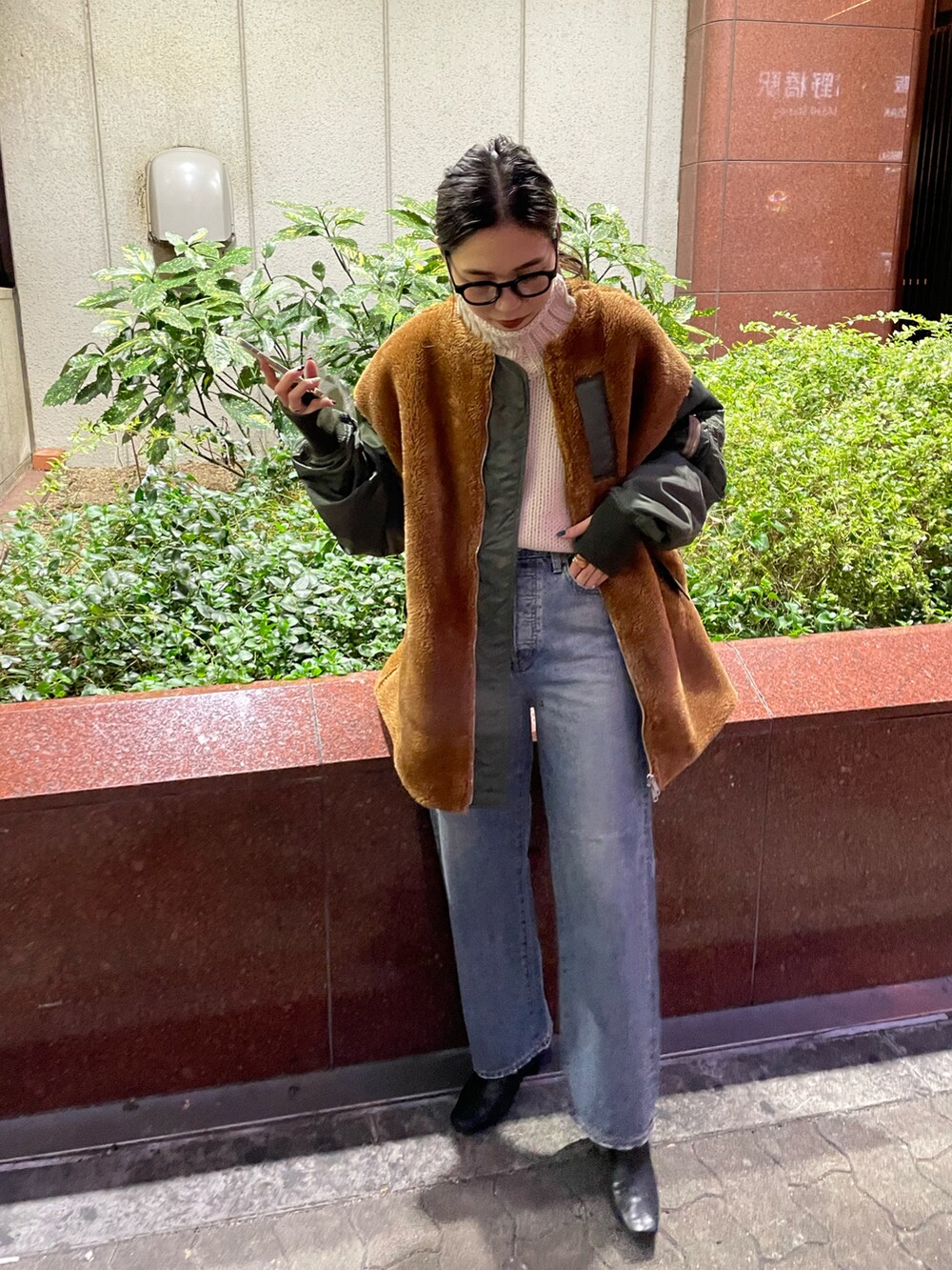 グリーン系のブルゾン、ブルー系のデニムパンツ、ホワイト系のニット/セーターを着用したレディースの秋コーディネートの4枚目の写真