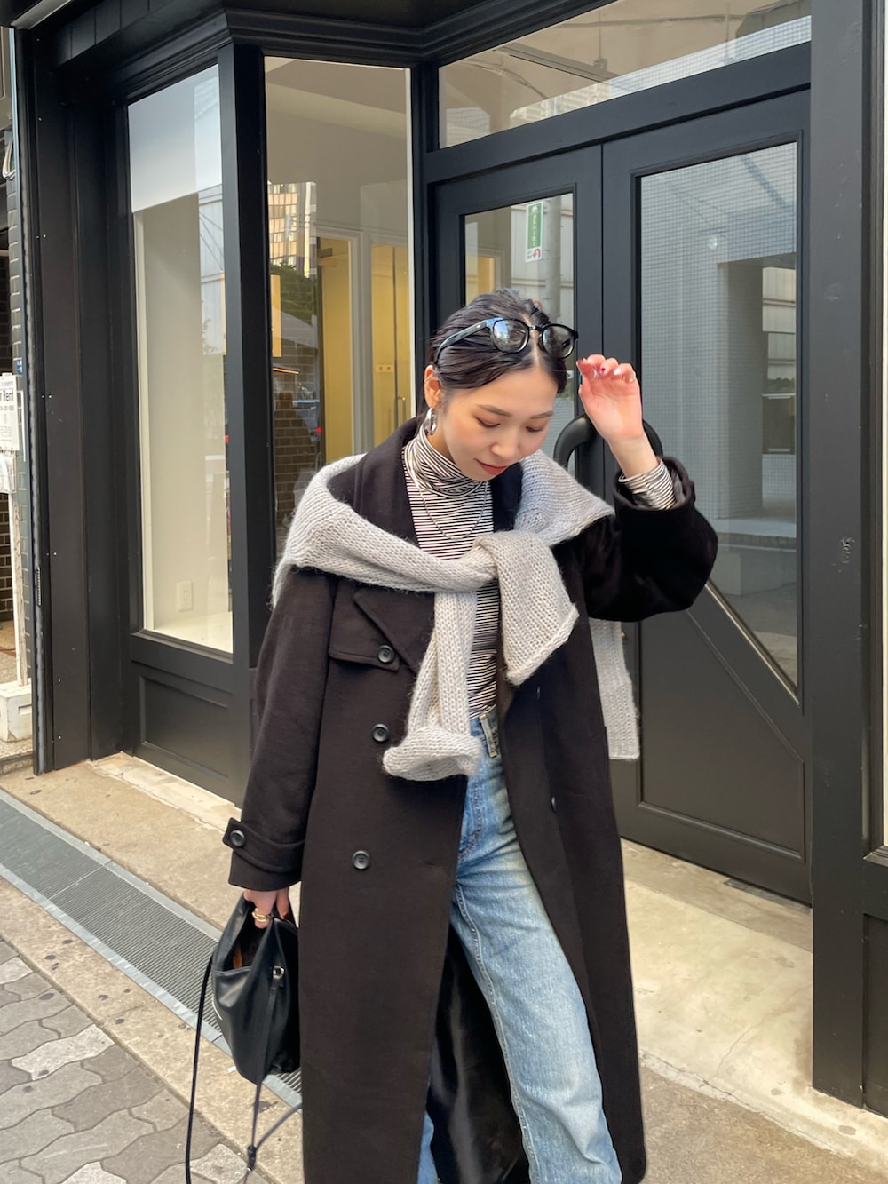 ブルー系のデニムパンツ、ブラック系のブーツ、ブラック系のチェスターコートを着用したレディースの秋コーディネートの3枚目の写真