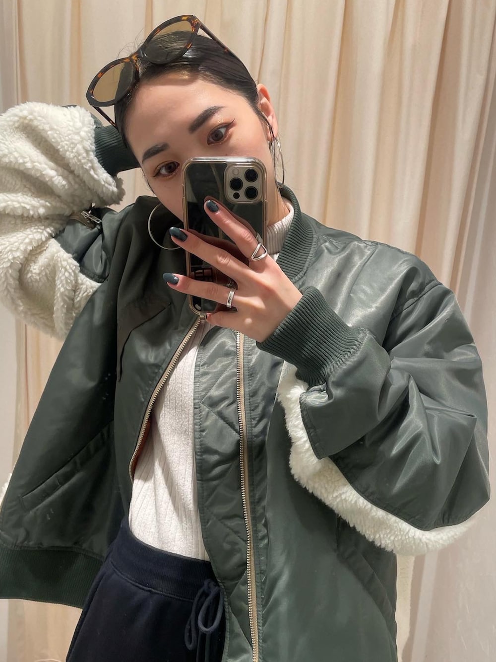 グリーン系のMA-1、ホワイト系のニット/セーター、ブラック系のスウェットパンツを着用したレディースの冬コーディネートの3枚目の写真