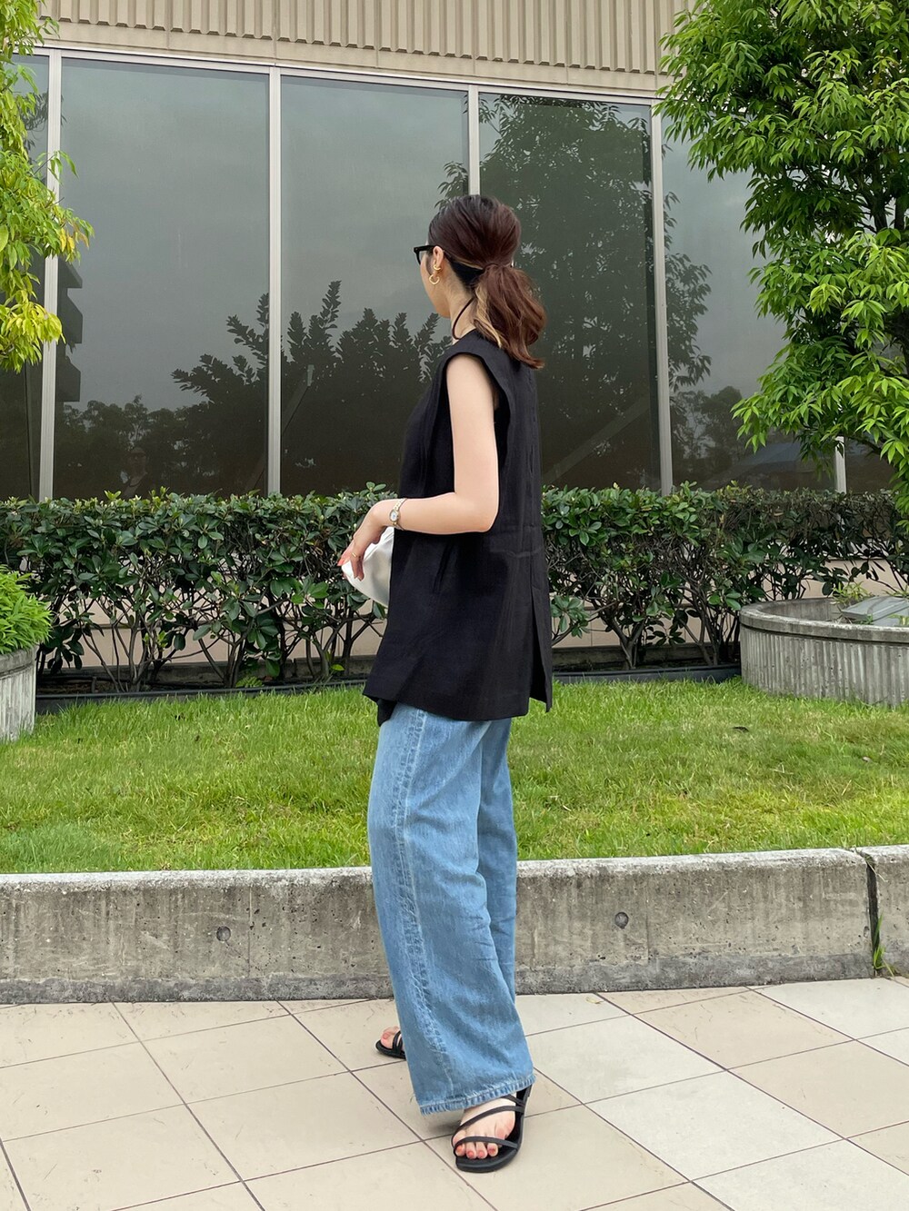 ホワイト系のタンクトップ、ブラック系のベスト、ブルー系のデニムパンツを着用したレディースの夏コーディネートの3枚目の写真