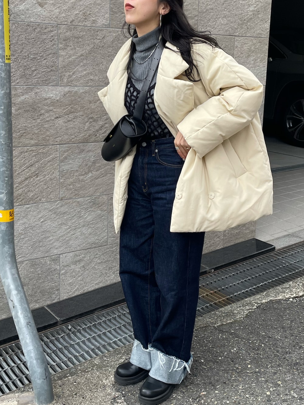 ブラック系のショルダーバッグ、ブルー系のデニムパンツ、ホワイト系のダウンジャケット/コートを着用したレディースの冬コーディネートの4枚目の写真