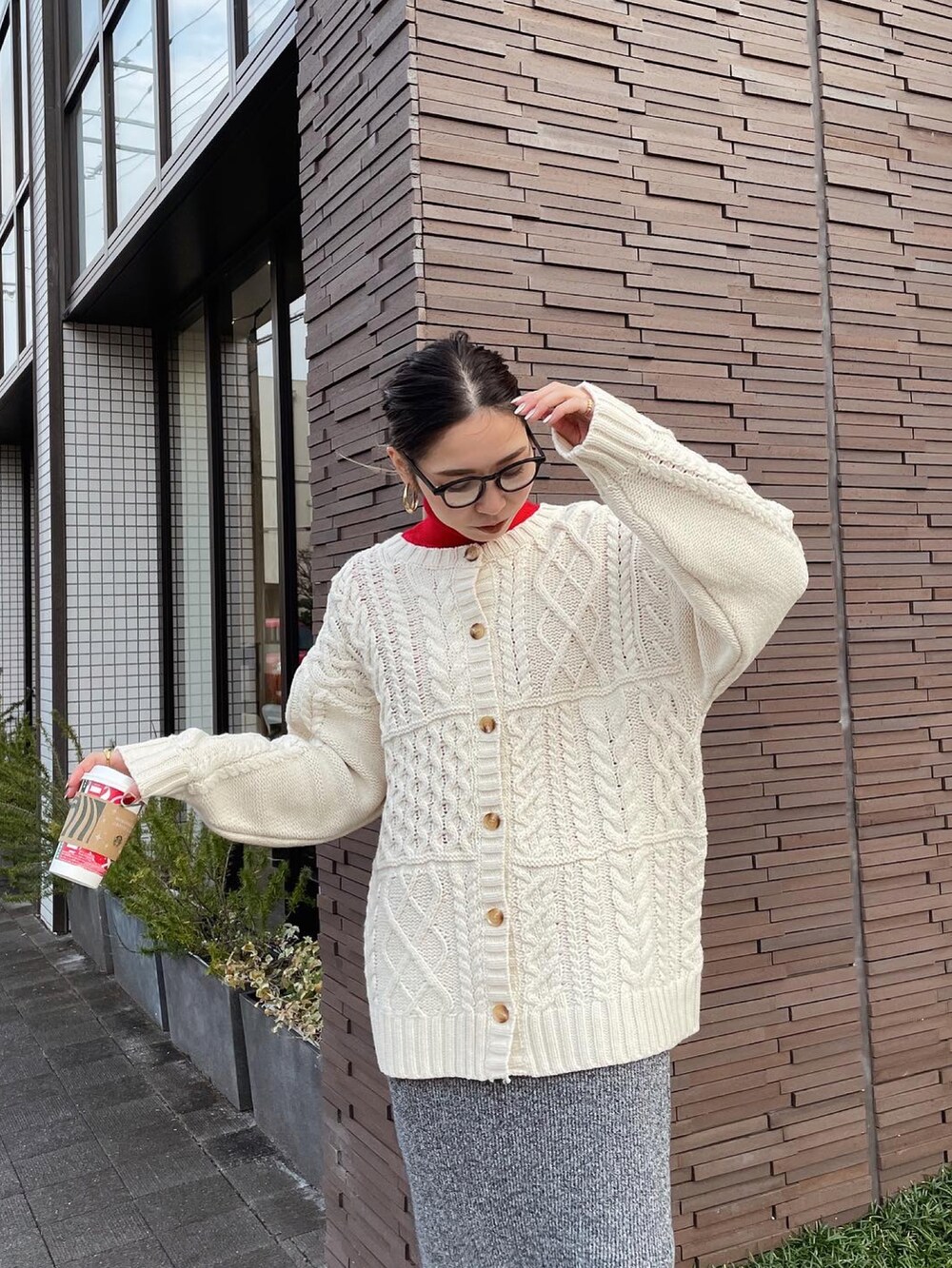 ホワイト系のカーディガン/ボレロ、レッド系のニット/セーター、グレー系のスカートを着用したレディースの冬コーディネートの4枚目の写真